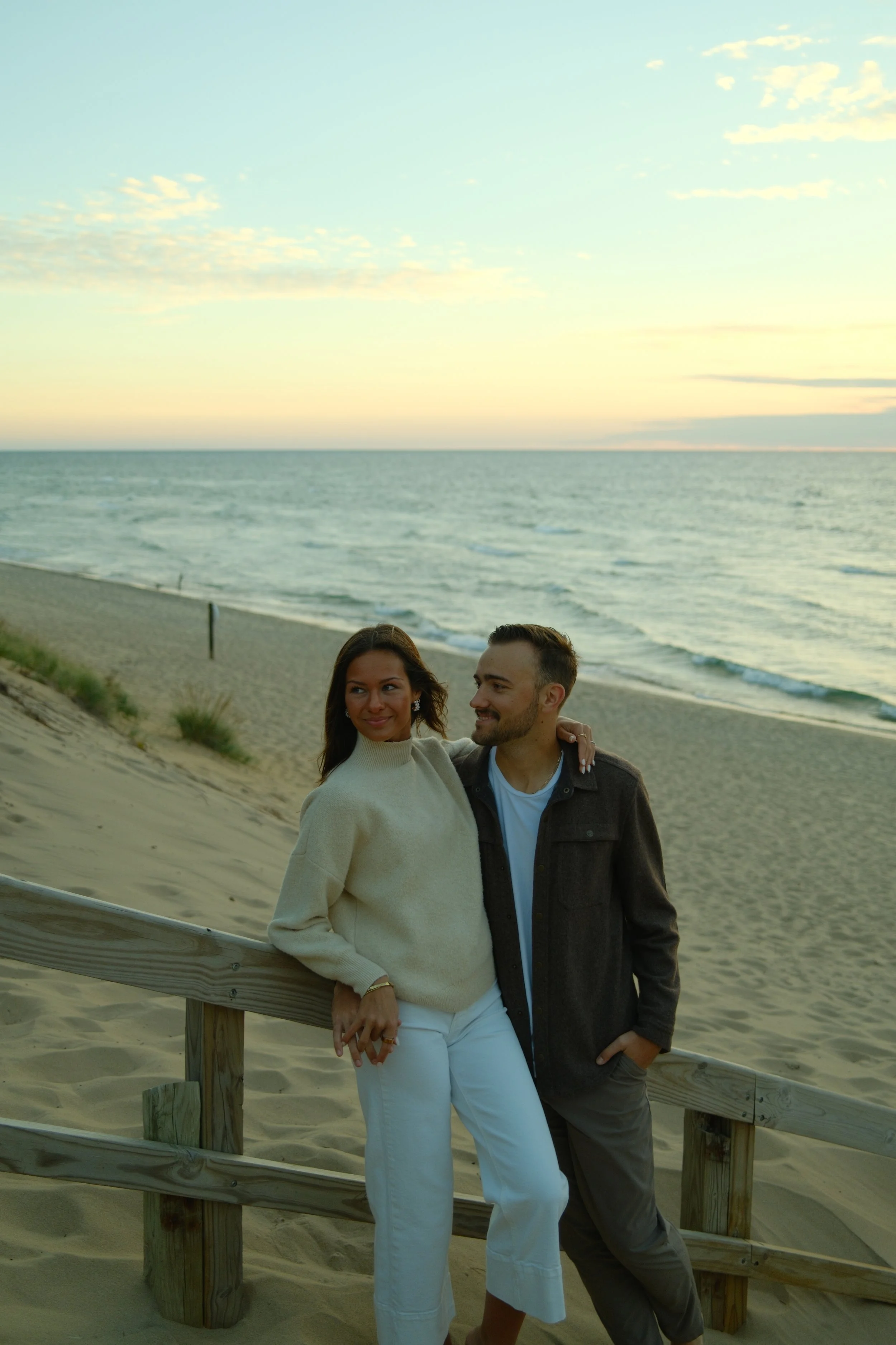 Couples engagement captured on film at West Michigan coastline beach during sunset with genuine connection.