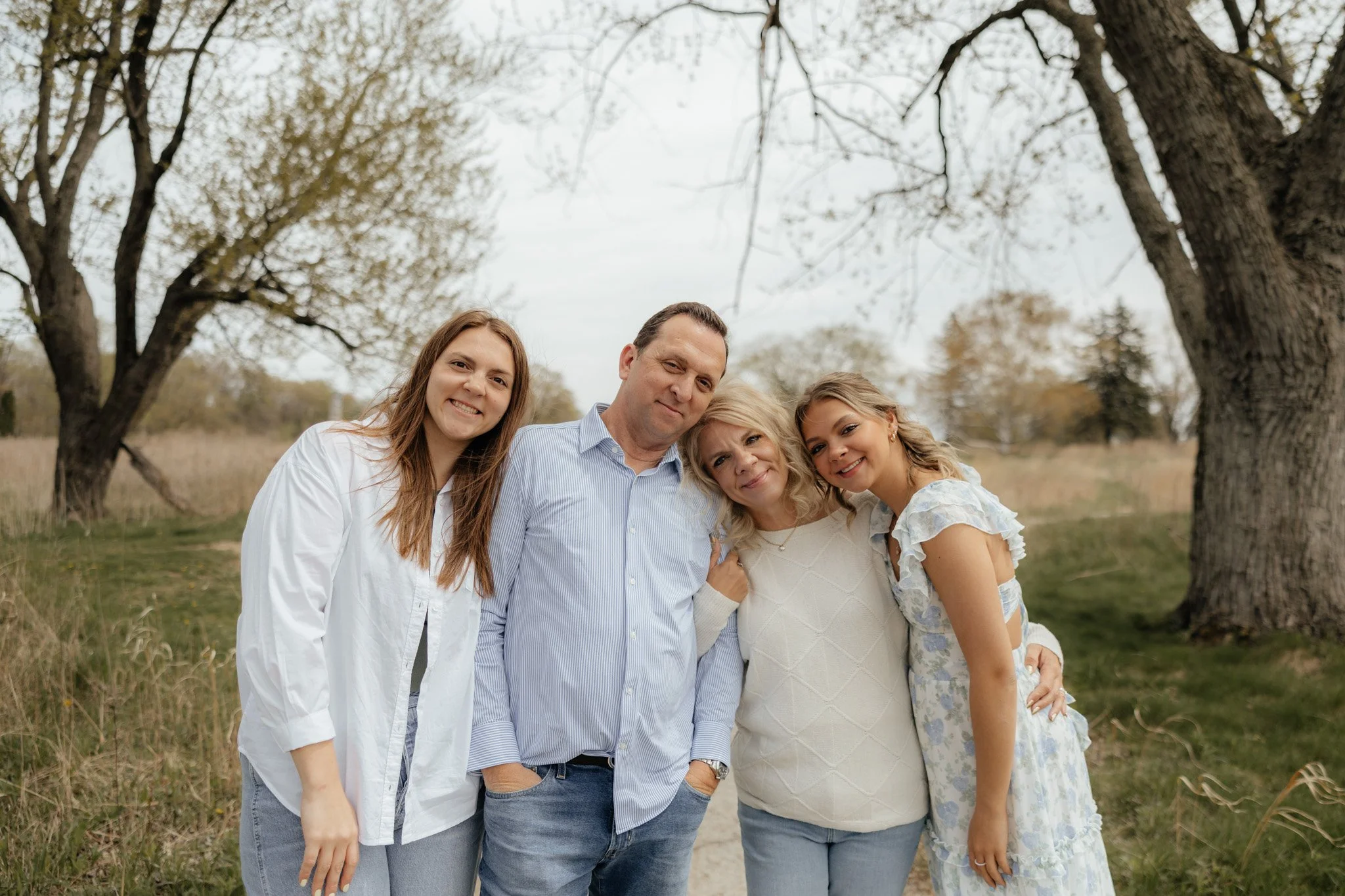 A family of five standing together outdoors in a grassy area with trees in the background at The Highlands in Grand Rapids, Michigan.