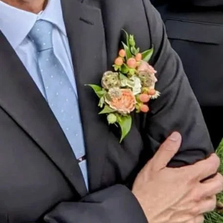 Man wearing a suit with a floral boutonniere on his lapel.