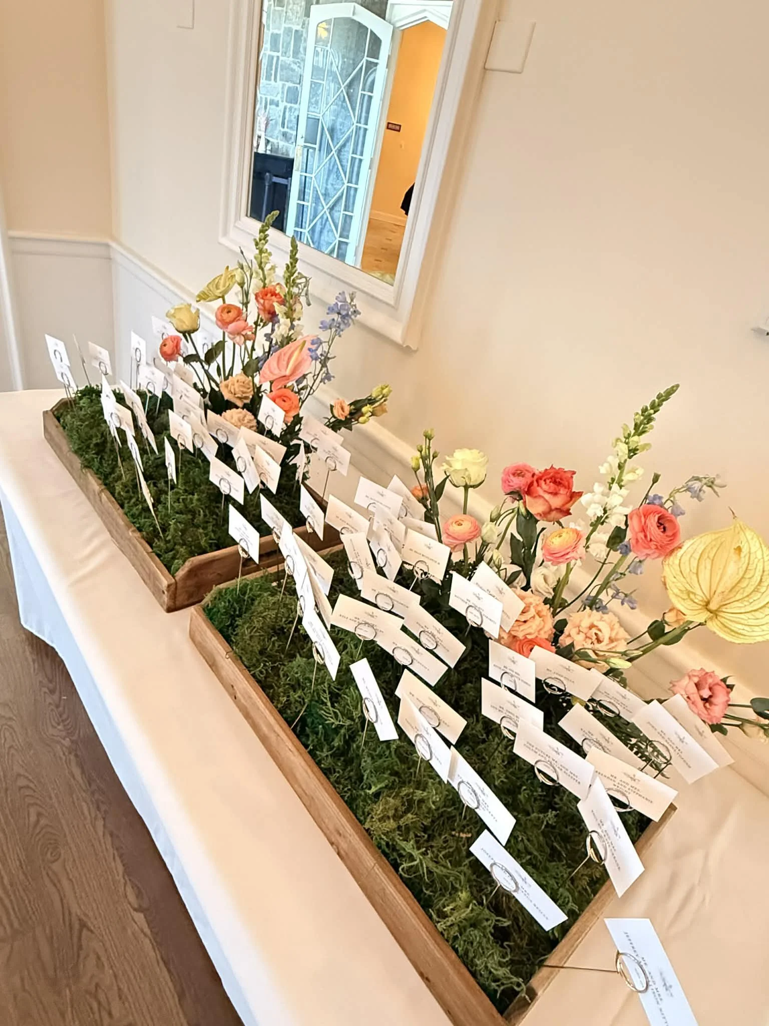 Floral arrangements with wedding table name tags on a table, decorated with moss and flowers designed by Lot 32 Flower Farm.