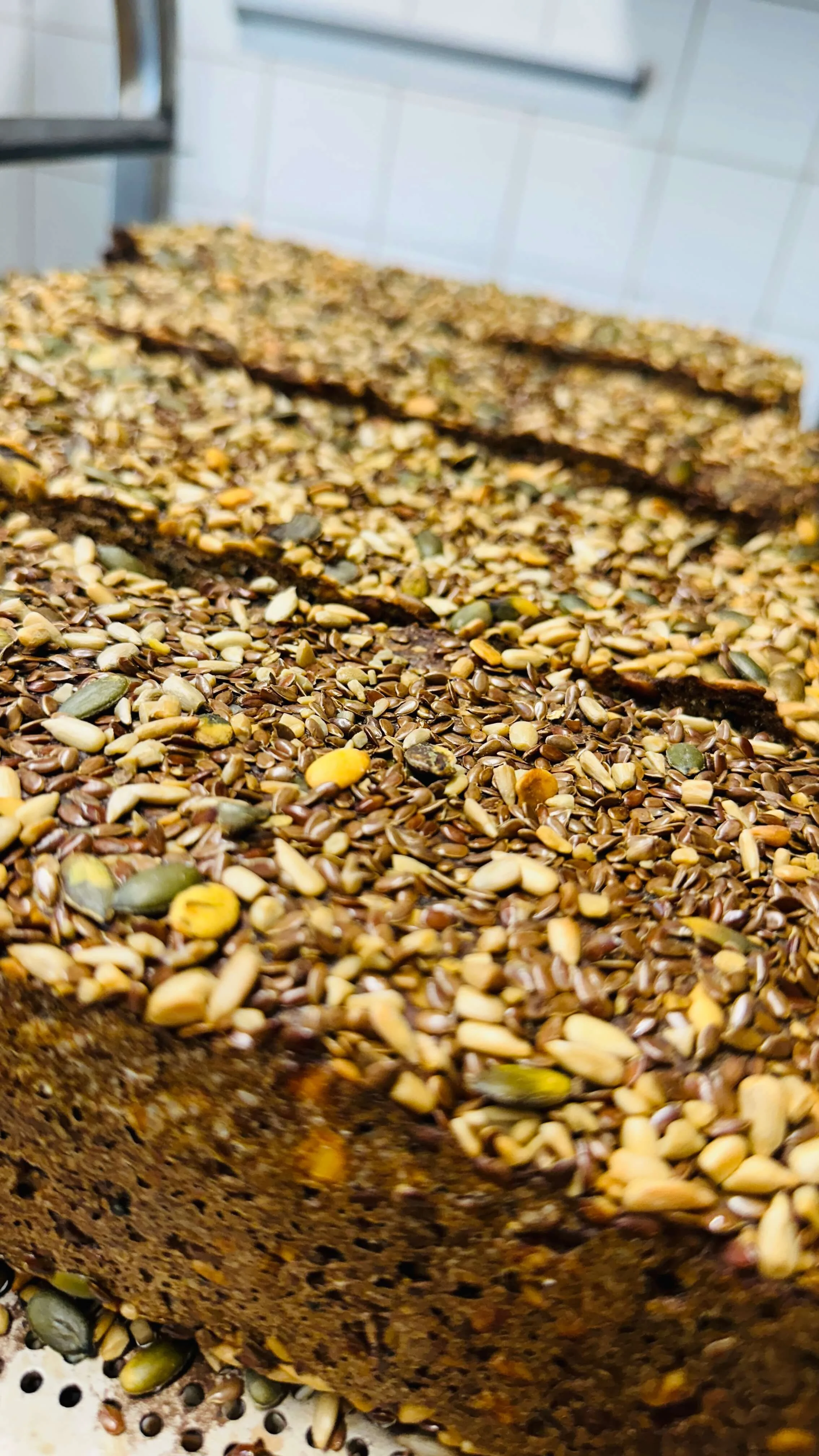 Close-up of a seed-covered bread with sliced pieces in the background.