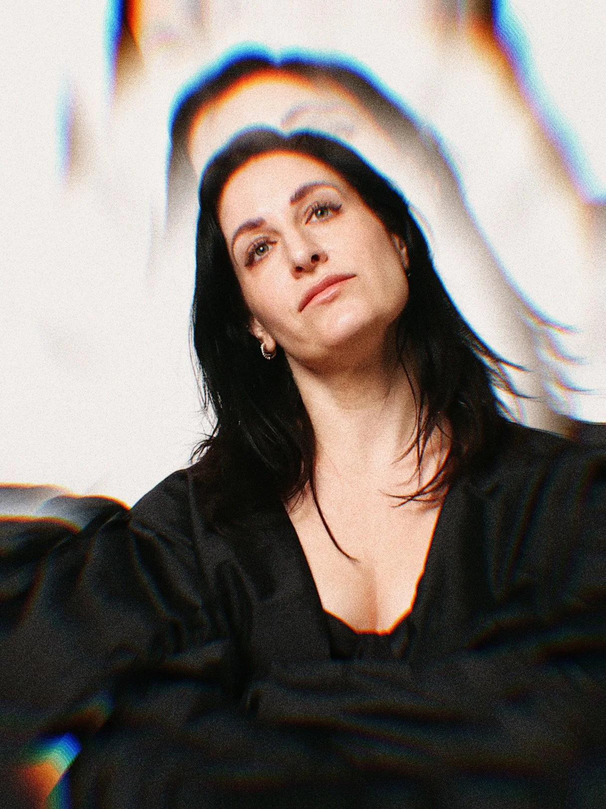 The lead singer, Nicole Cassese, a woman with black hair and a thoughtful expression. She is styled in a black ensemble and the image is treated with a kaleidoscopic radial effect.