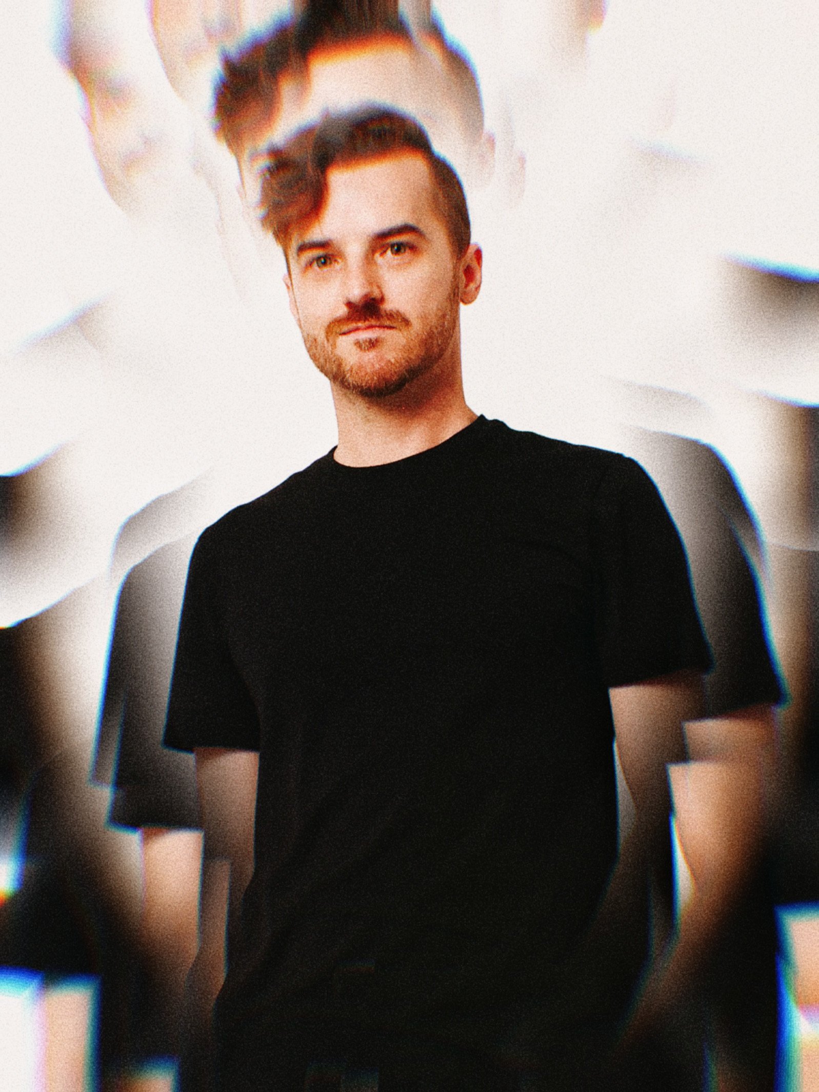 A feature of one of the lead musicians, Mike Horton,  shown with brown hair, a beard, and light skin, wearing a black T-shirt, standing against a light background with a kaleidoscopic visual effect creating multiple layered copies of his image.