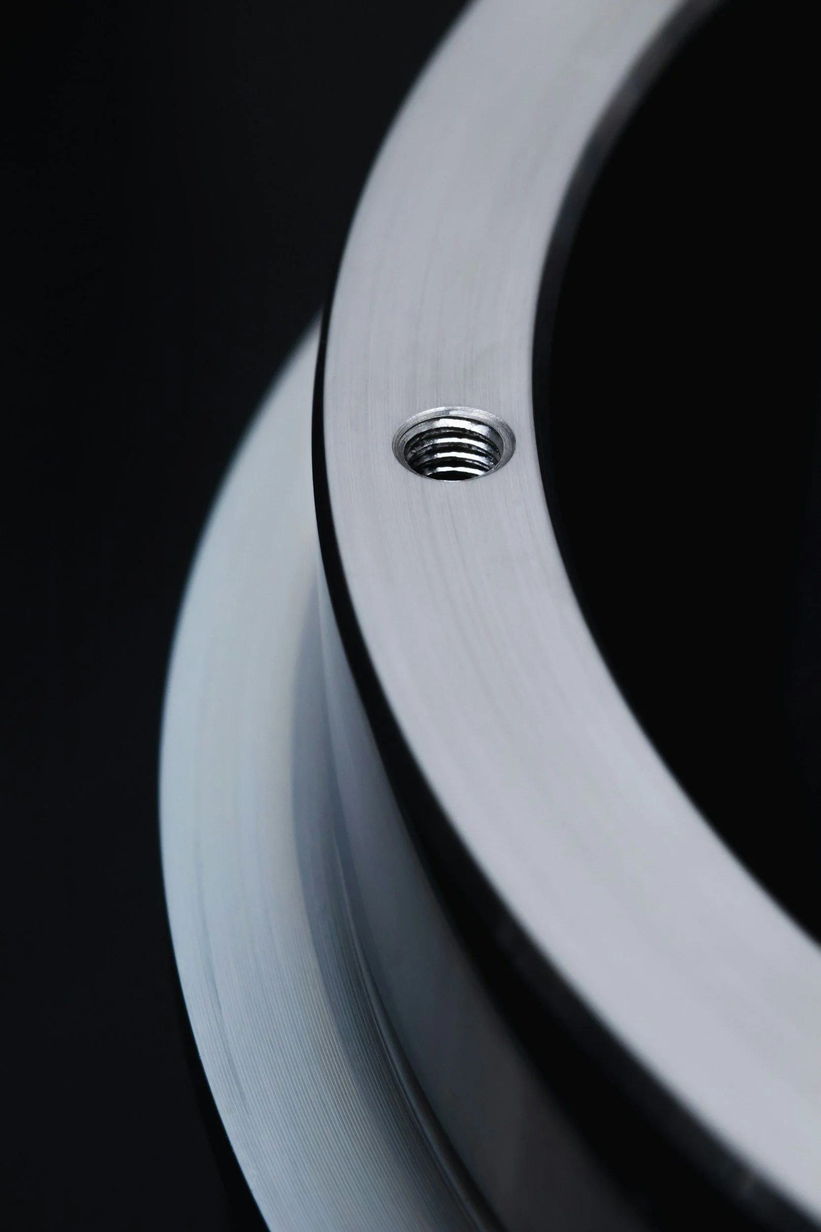 Close-up of a metallic circular object with a threaded hole in the center, against a dark background.