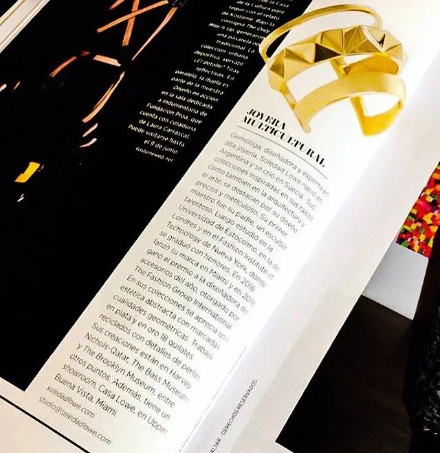 A page from a magazine featuring a pair of gold headphones hanging over the top of the page and a gold ring beside them. The page contains text in Spanish about a person named Tober.