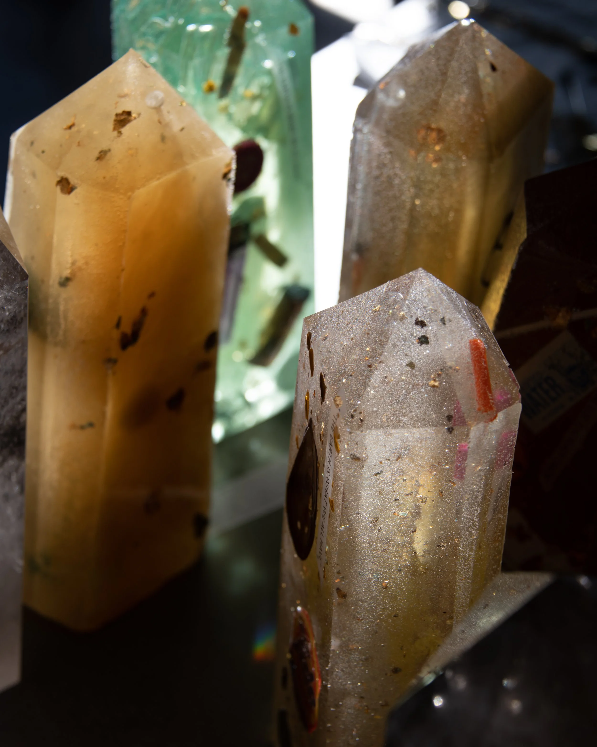 Close-up of several mineral or gemstone crystals with different colors and textures, showing a range of yellow, green, clear, and dark brown stones.
