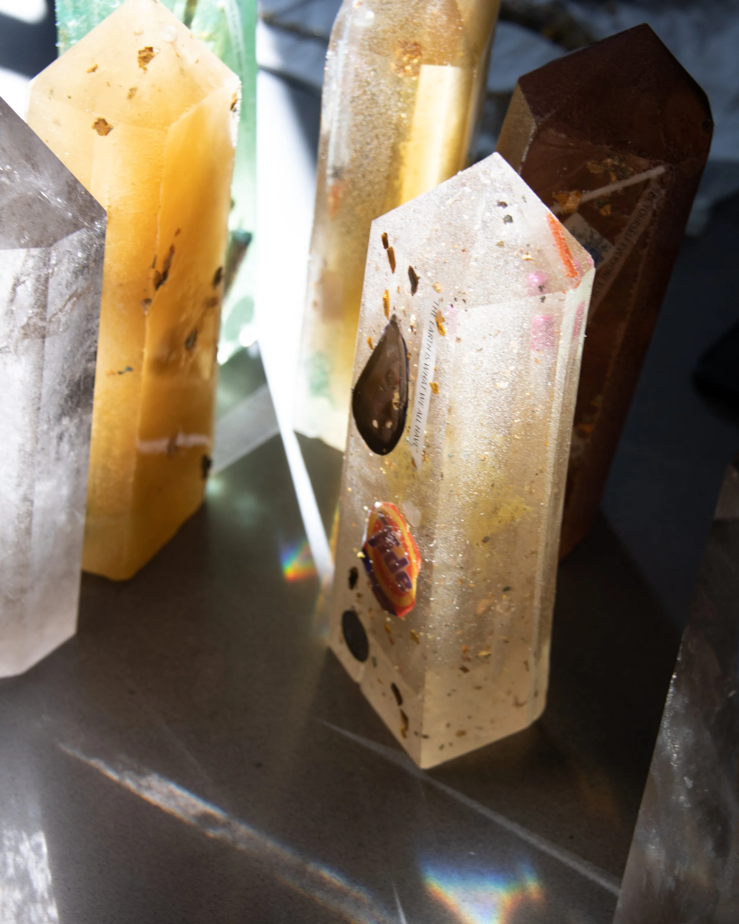 Close-up of a collection of decorative resin and gemstone sculptures with sunlight creating rainbow reflections.