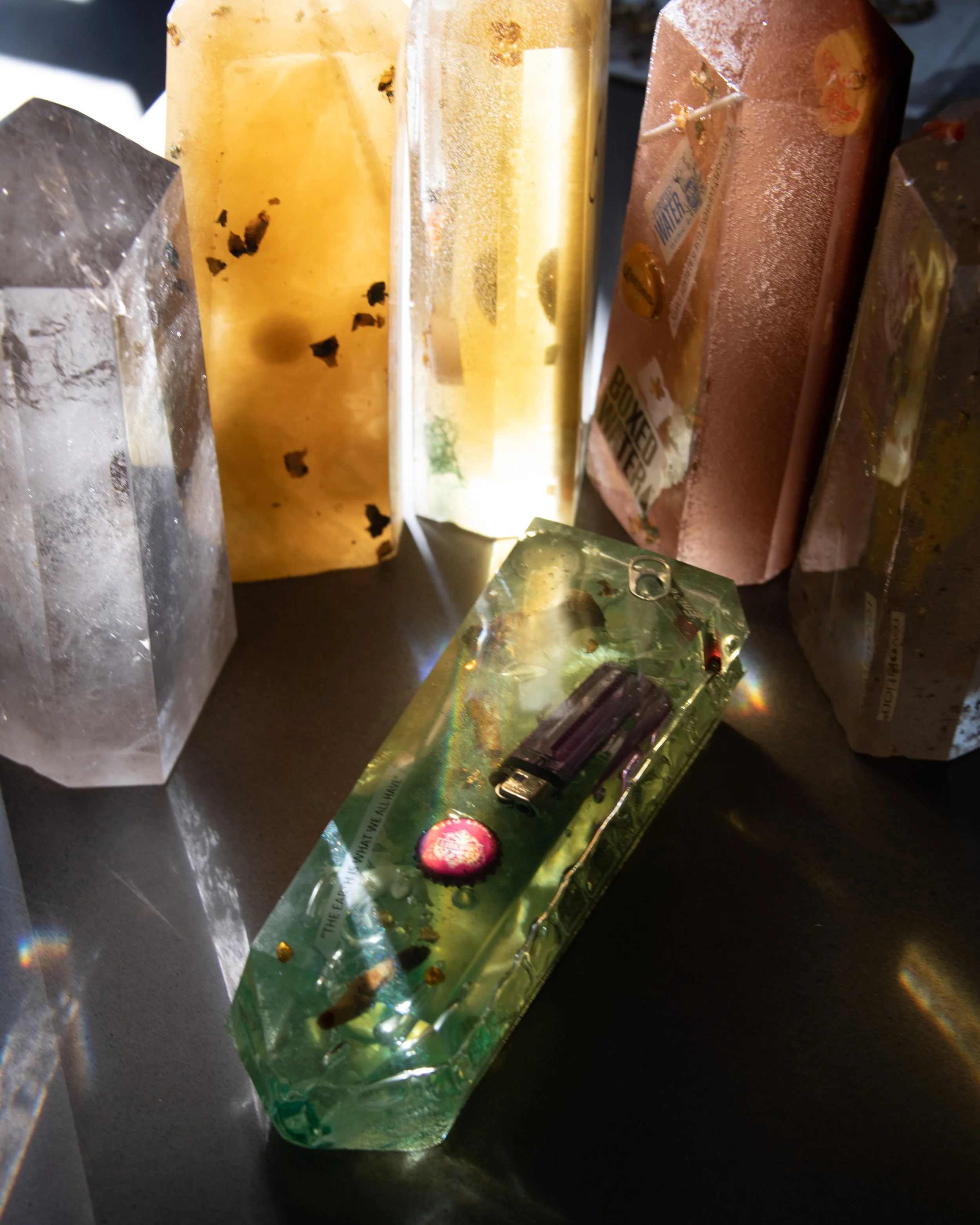 A collection of colorful soap bars and a decorative glass piece with embedded objects, placed on a dark surface.