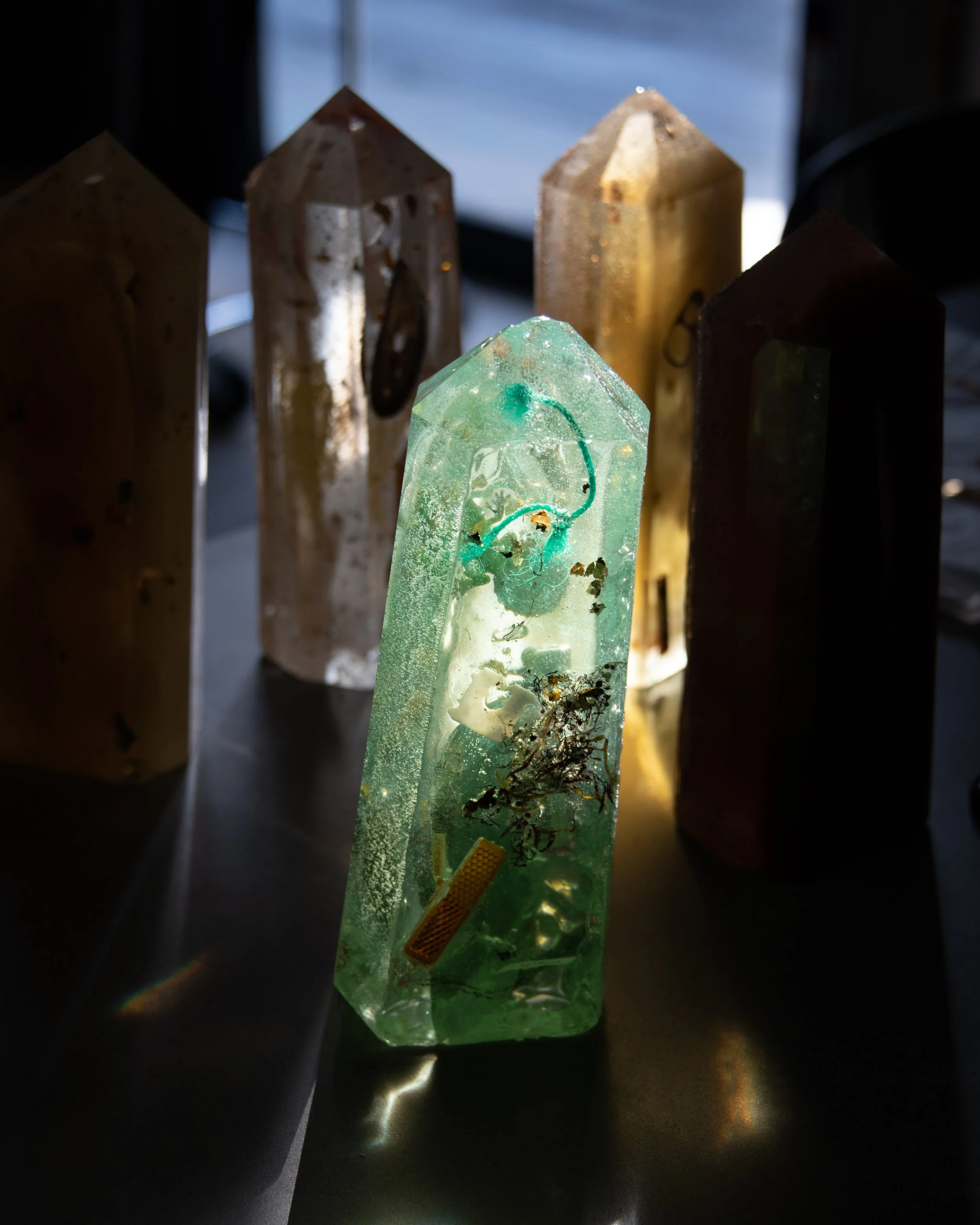 Collection of large, translucent crystals with a green crystal in the foreground, illuminated from below, with a dark background.