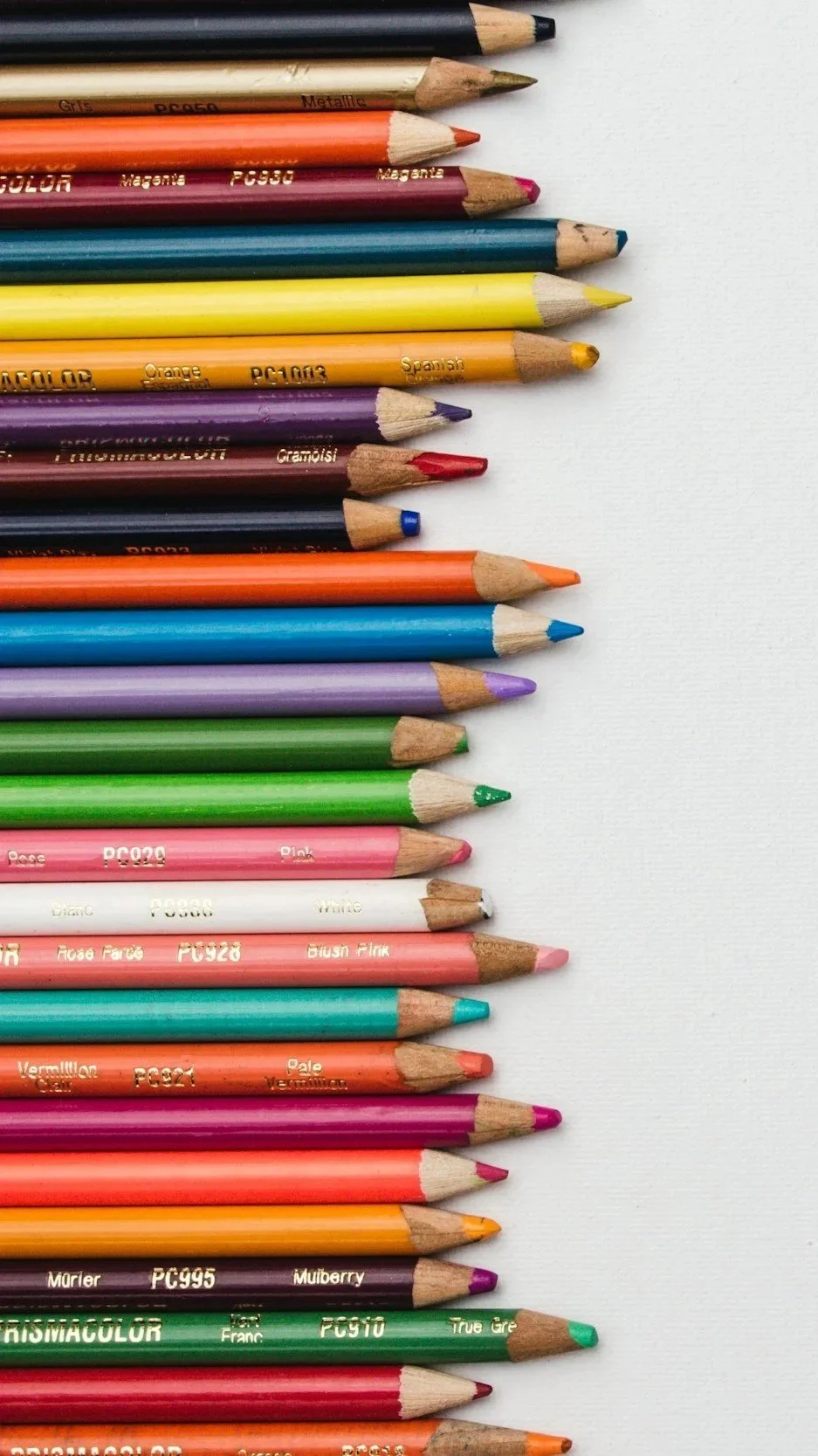 Color pencils arranged in a row on a white surface, with some sharpened tips visible.