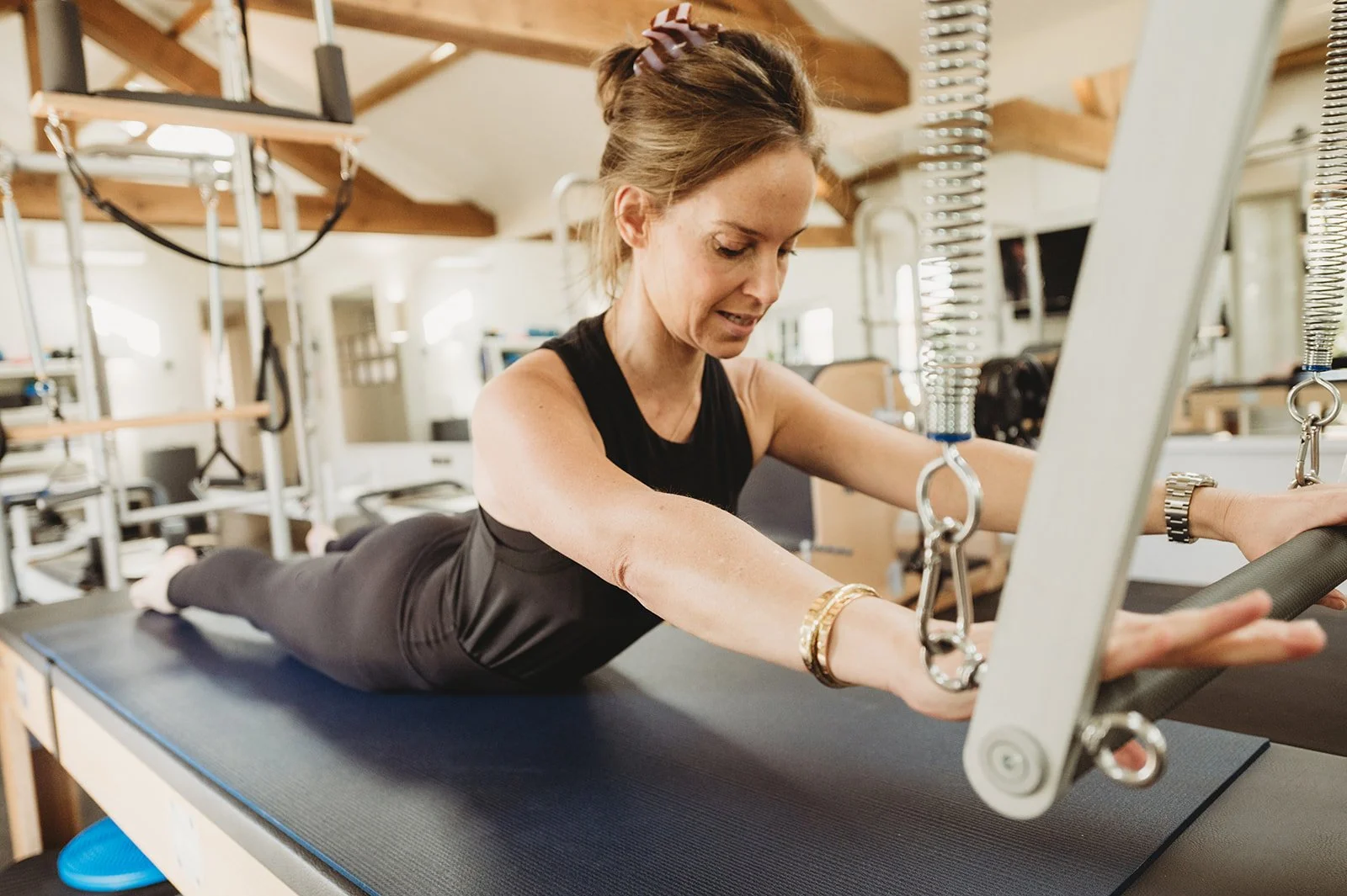 Pilates teacher uses both hands to brace the bar on the reformer