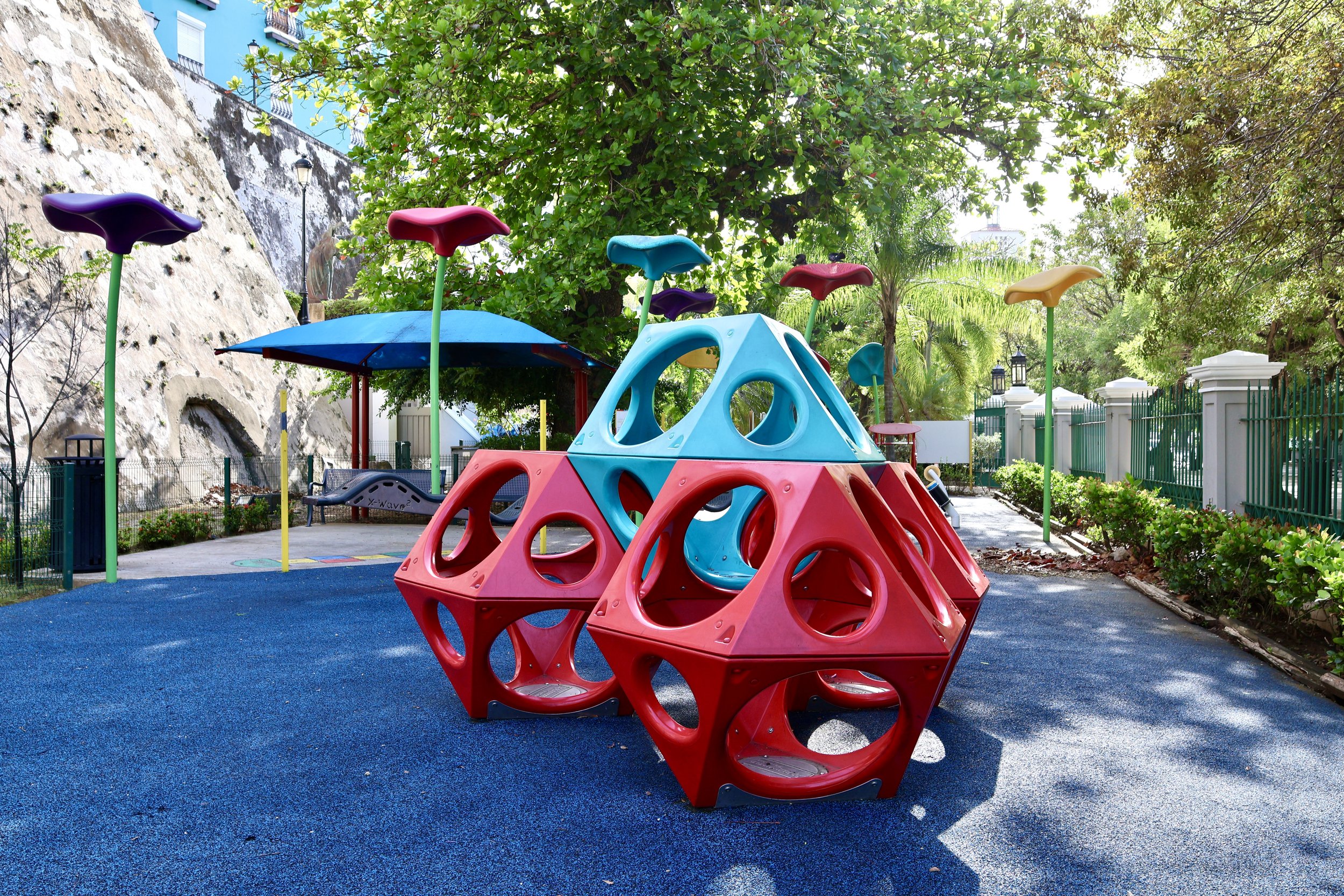 Colorful modern playground equipment with geometric structures in a park with trees and a blue surface
