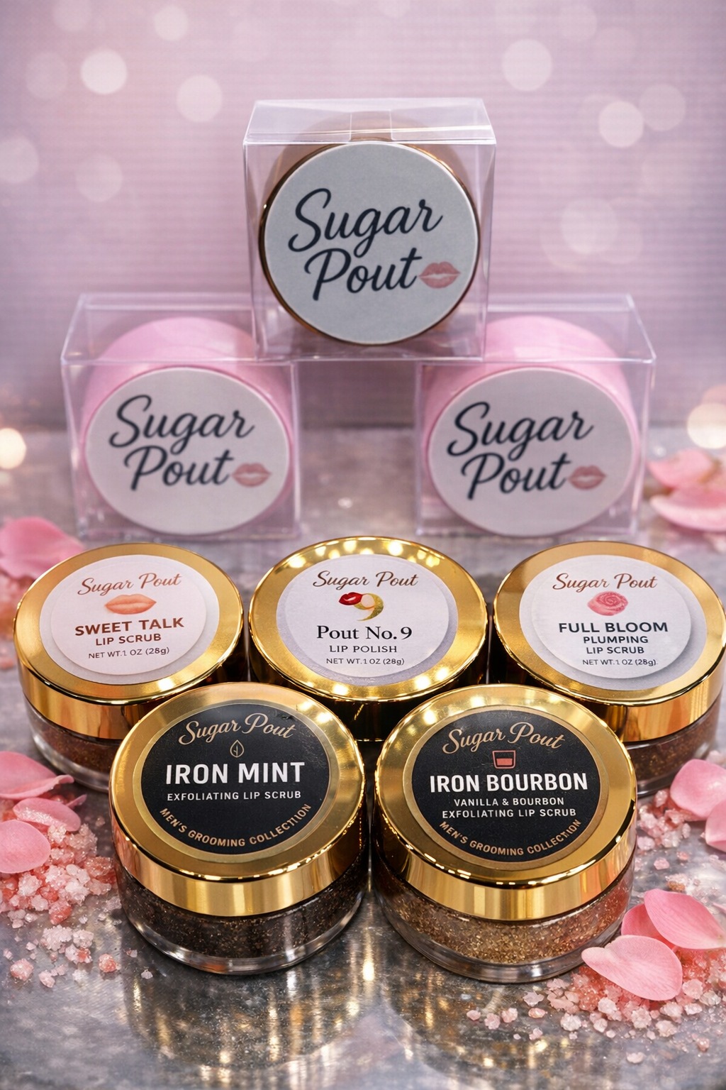 Display of Sugar Pout lip scrubs and lip polishes in jars and boxes, with pink rose petal decorations in the background.