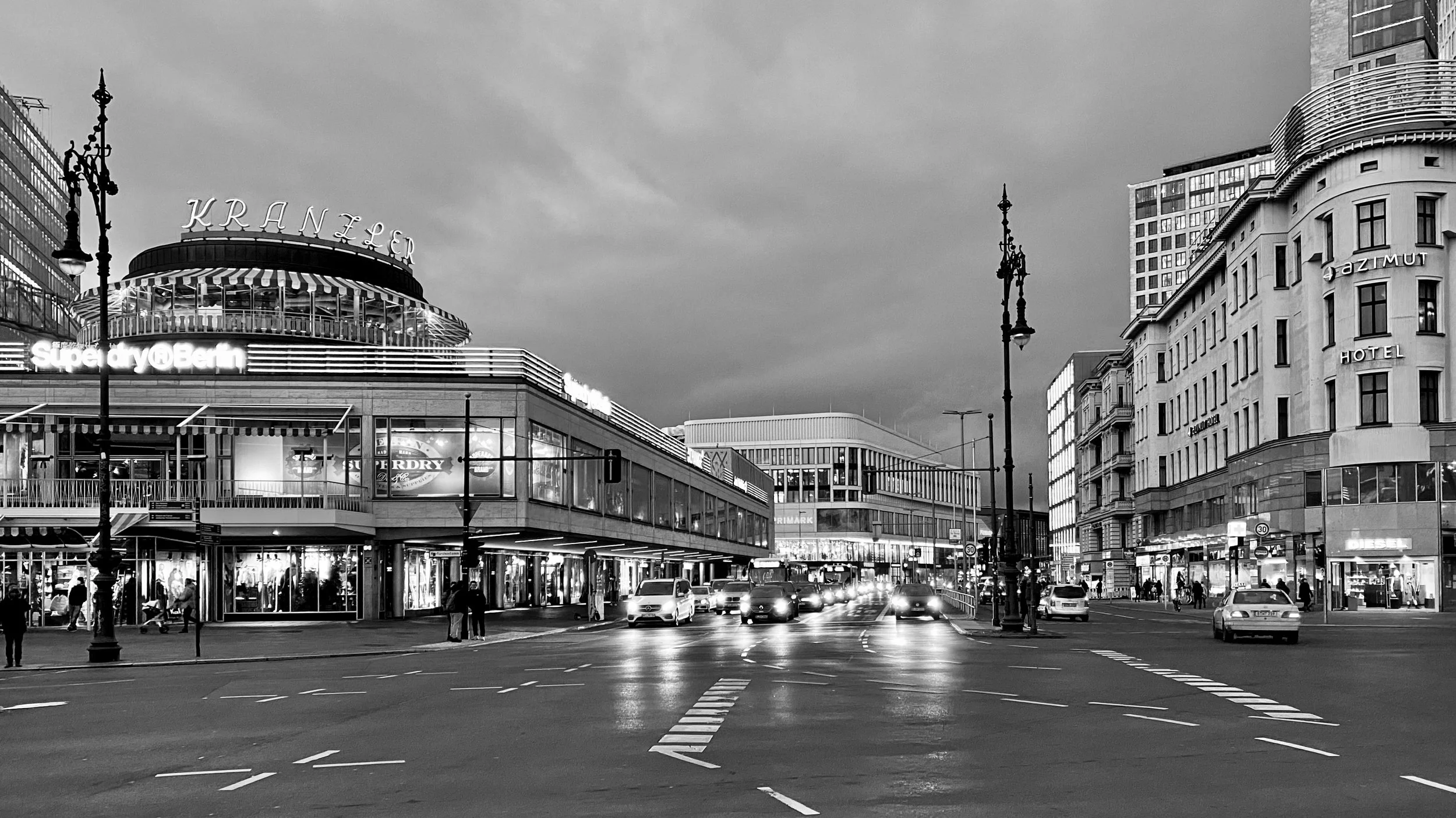 Stadtansicht mit Straßen, Autos, modernen Gebäuden und einem zweistöckigen Gebäude mit Neon-Schildern in Berlin, bei Dämmerung