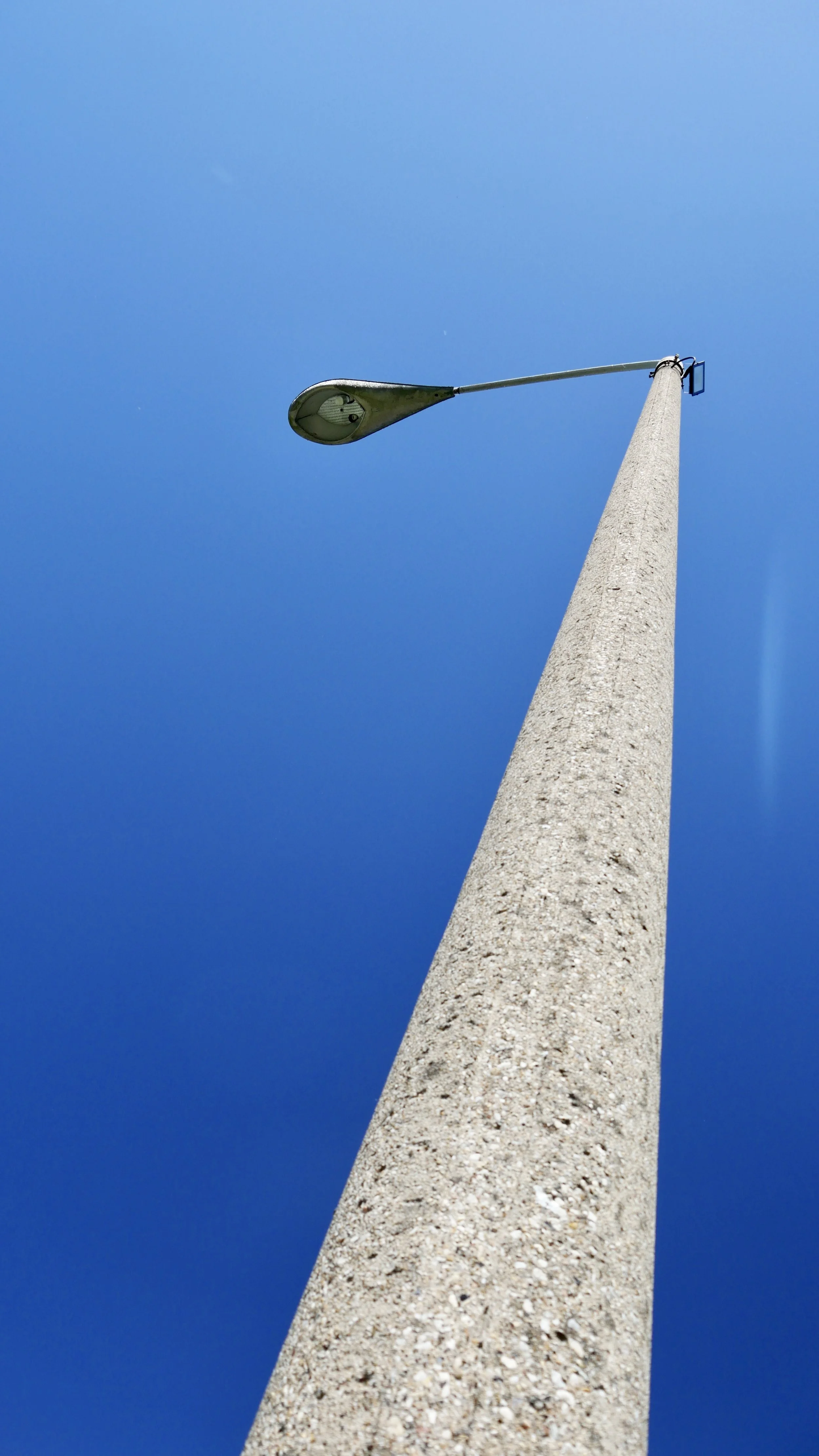 Moderner Straßenlaterne auf einem hohen Betonpfosten gegen einen klaren blauen Himmel