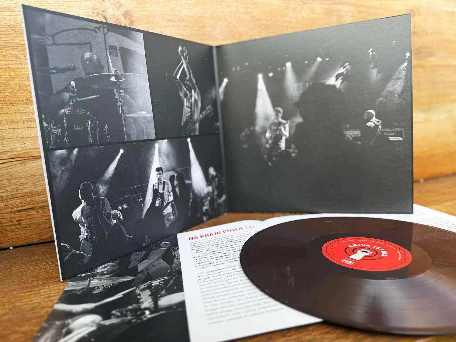 A vinyl record and a black-and-white concert photo booklet on a wooden surface.