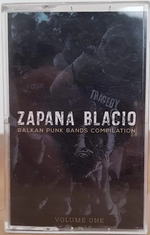 Cover of a music compilation titled 'Zapana Blacio Balkan Punk Bands Compilation' with 'Volume One' at the bottom. The cover features a black-and-white photo of a protesting crowd with some in punk attire.