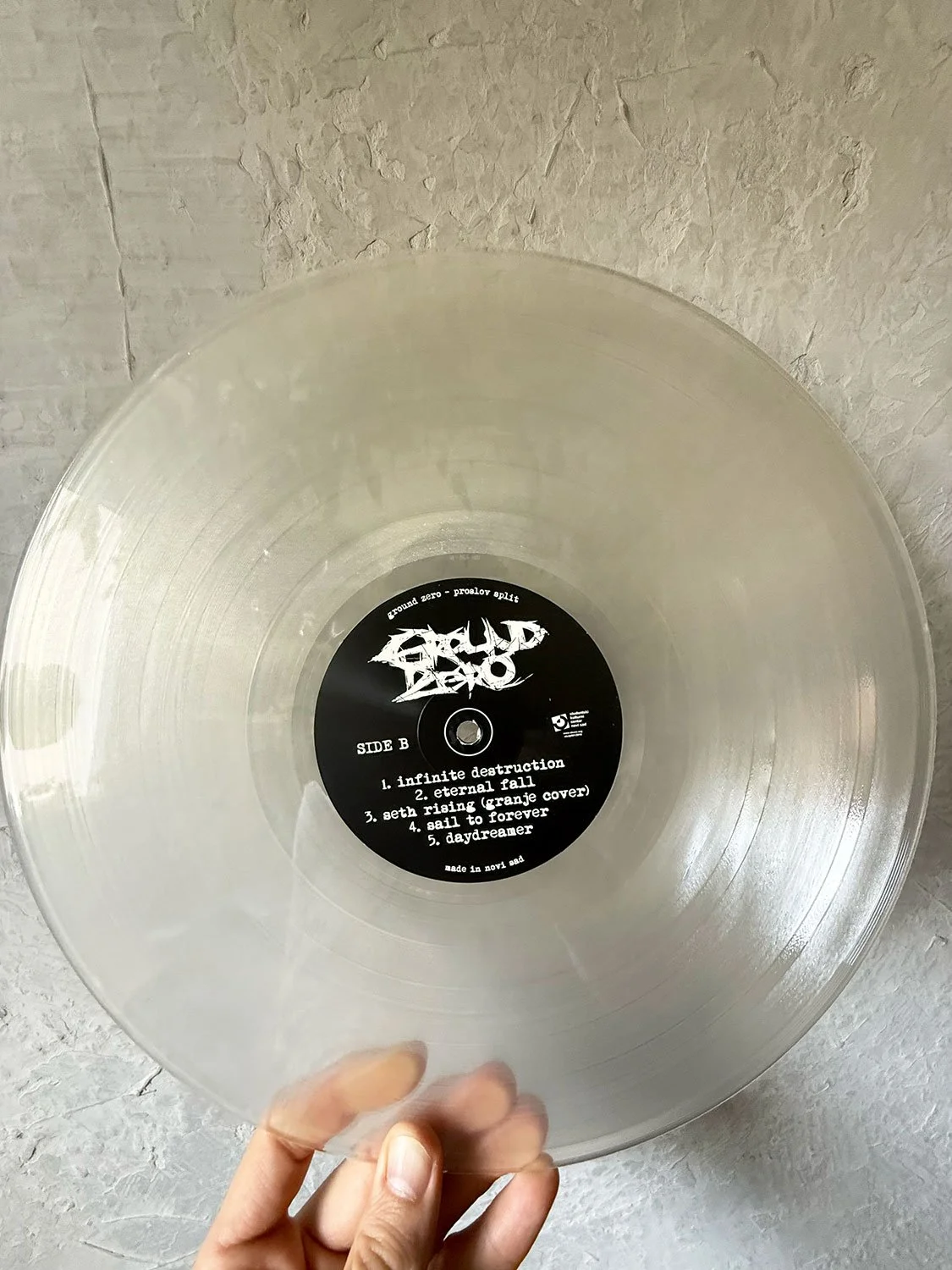 A clear vinyl record with a black circular label at the center. The label has white text listing five song titles and a stylized logo of the band 'Gulp Destroyer'.