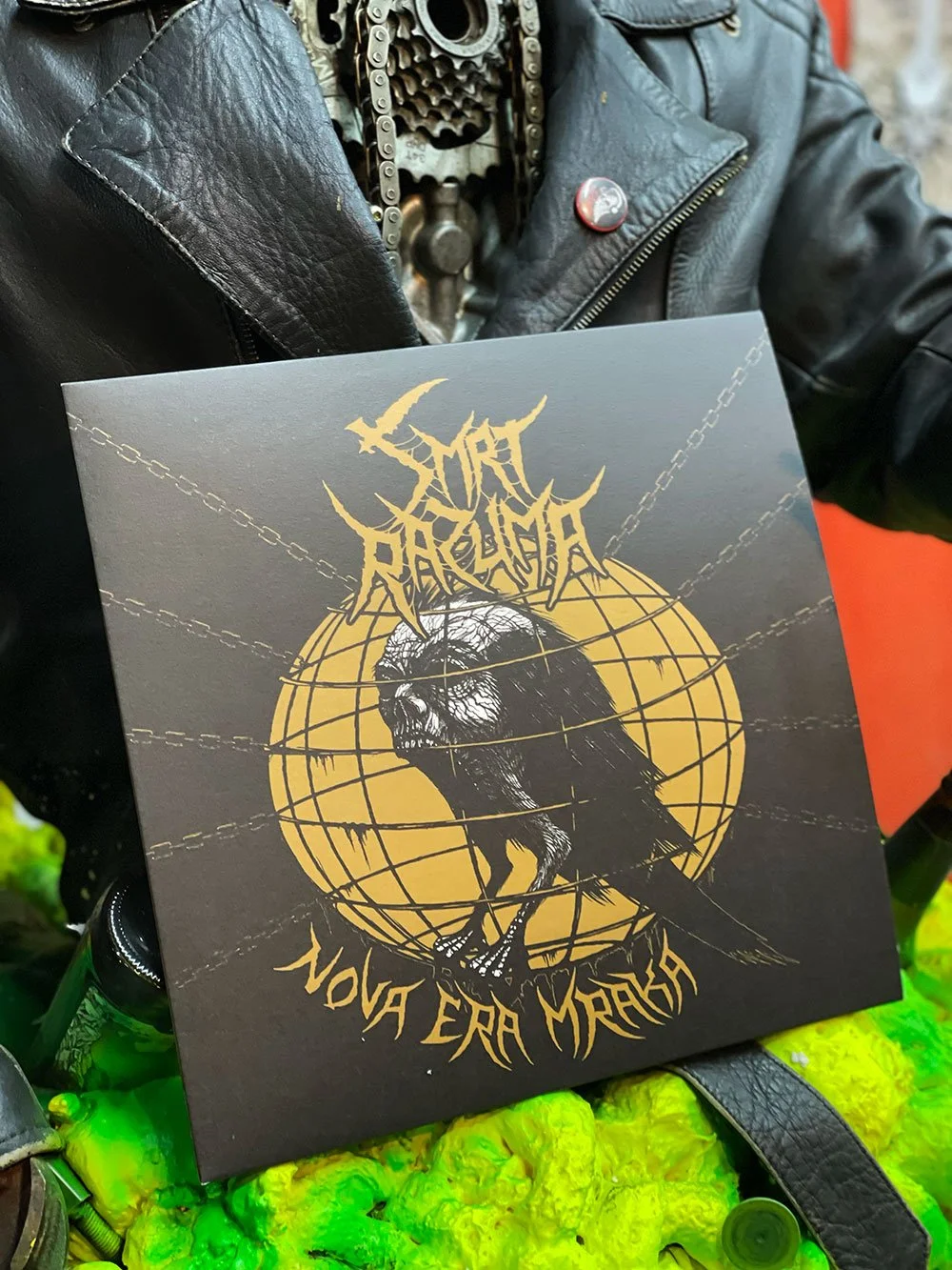 A black album cover with a yellow circle featuring a black bird with a skull-like face, superimposed on a world map grid. The band name 'Smrt Razuma' is written in jagged yellow text at the top, and the album title 'Nova Era Mraka' is at the bottom.