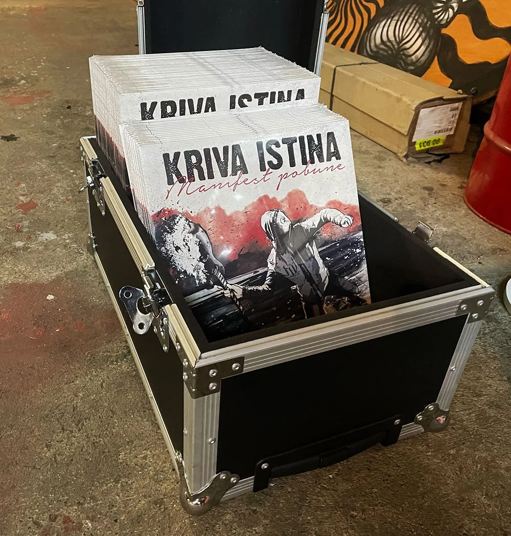 Display of pamphlets or flyers for Kriva Istina, featuring an illustration of two individuals holding hands, with a background that includes red and black artistic elements.