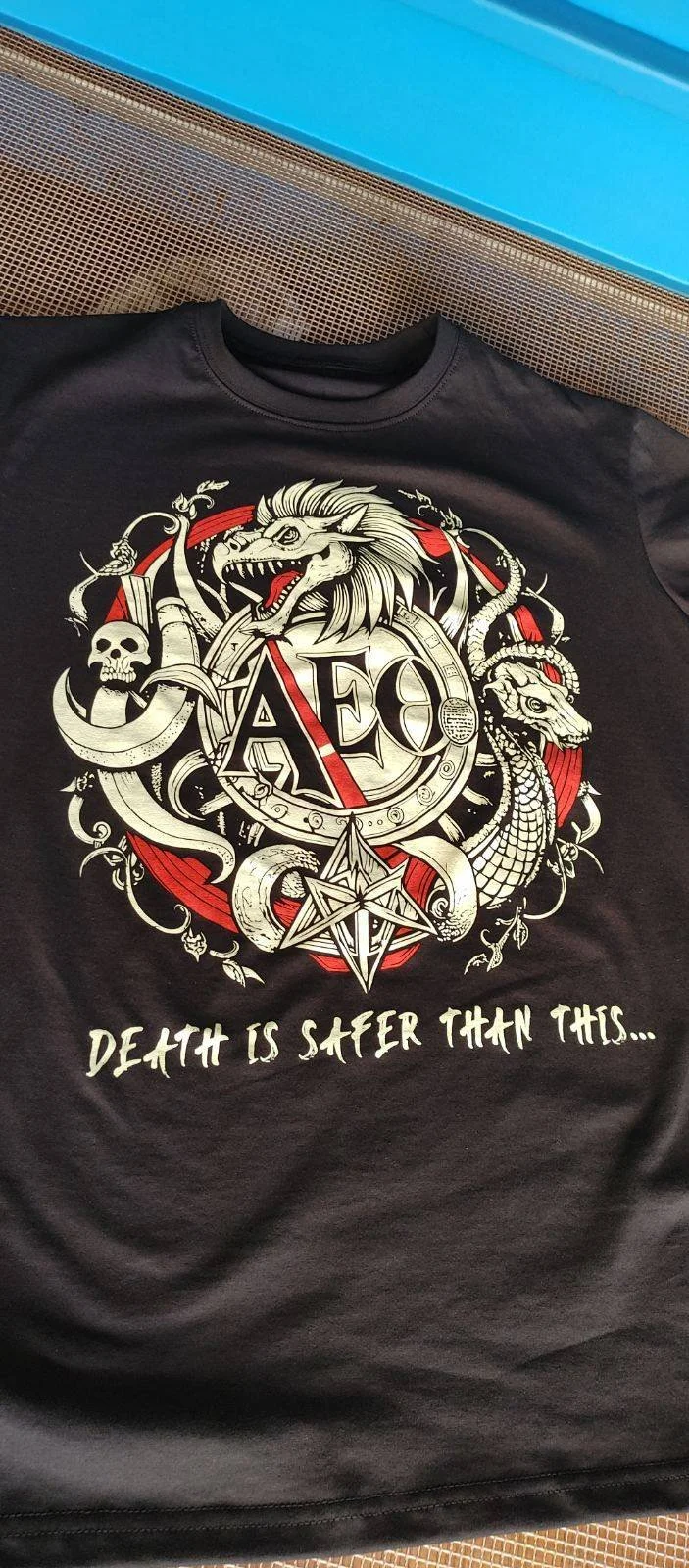 Black T-shirt with graphic design featuring a dragon, a unicorn, a skull, and a pentagram, with the text 'Death is safer than this...' in white.