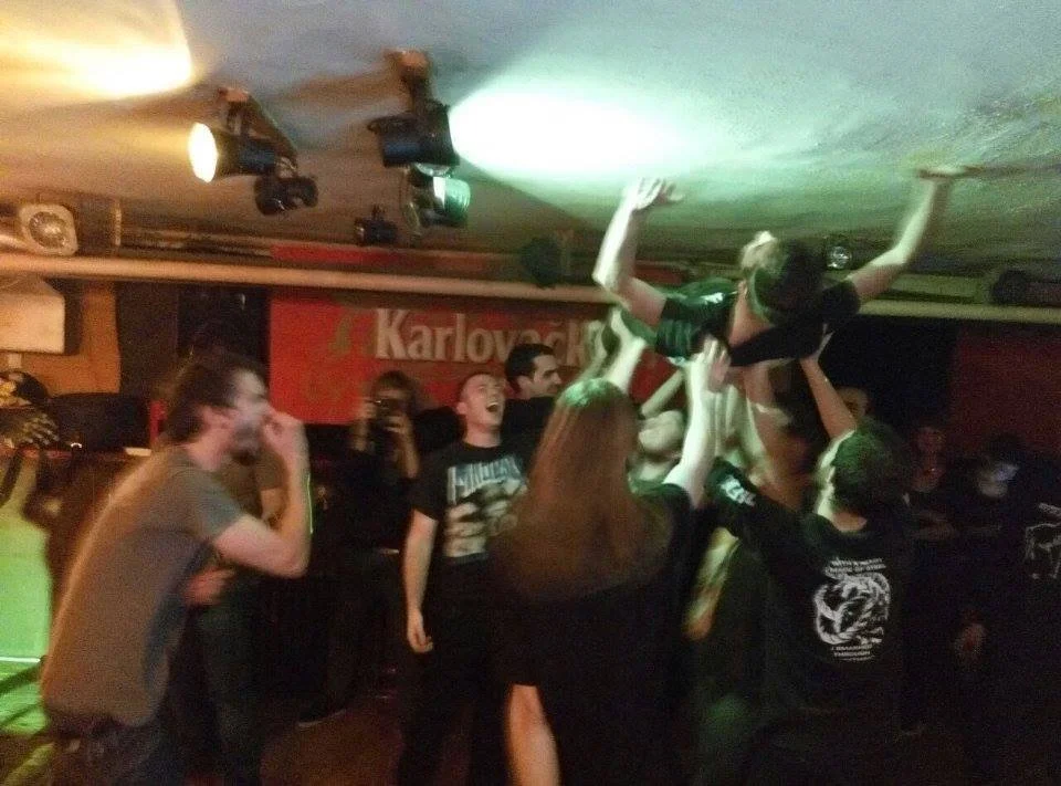 A group of people dancing and celebrating at a party or concert, lifting a person into the air.