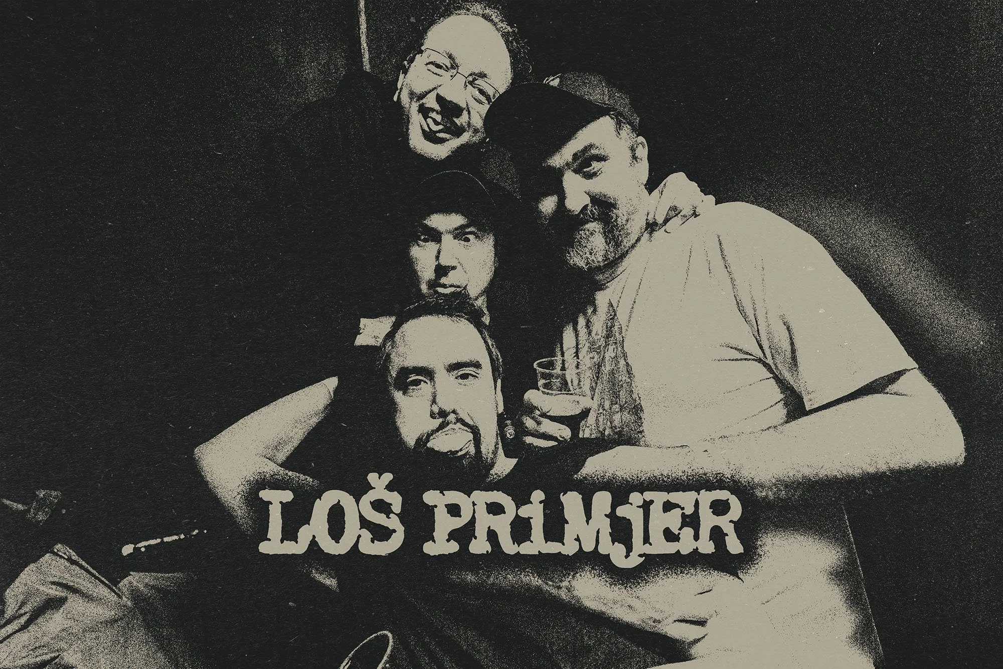 Four band members from LOS PRIMJER smiling and posing for a photo at a gathering.