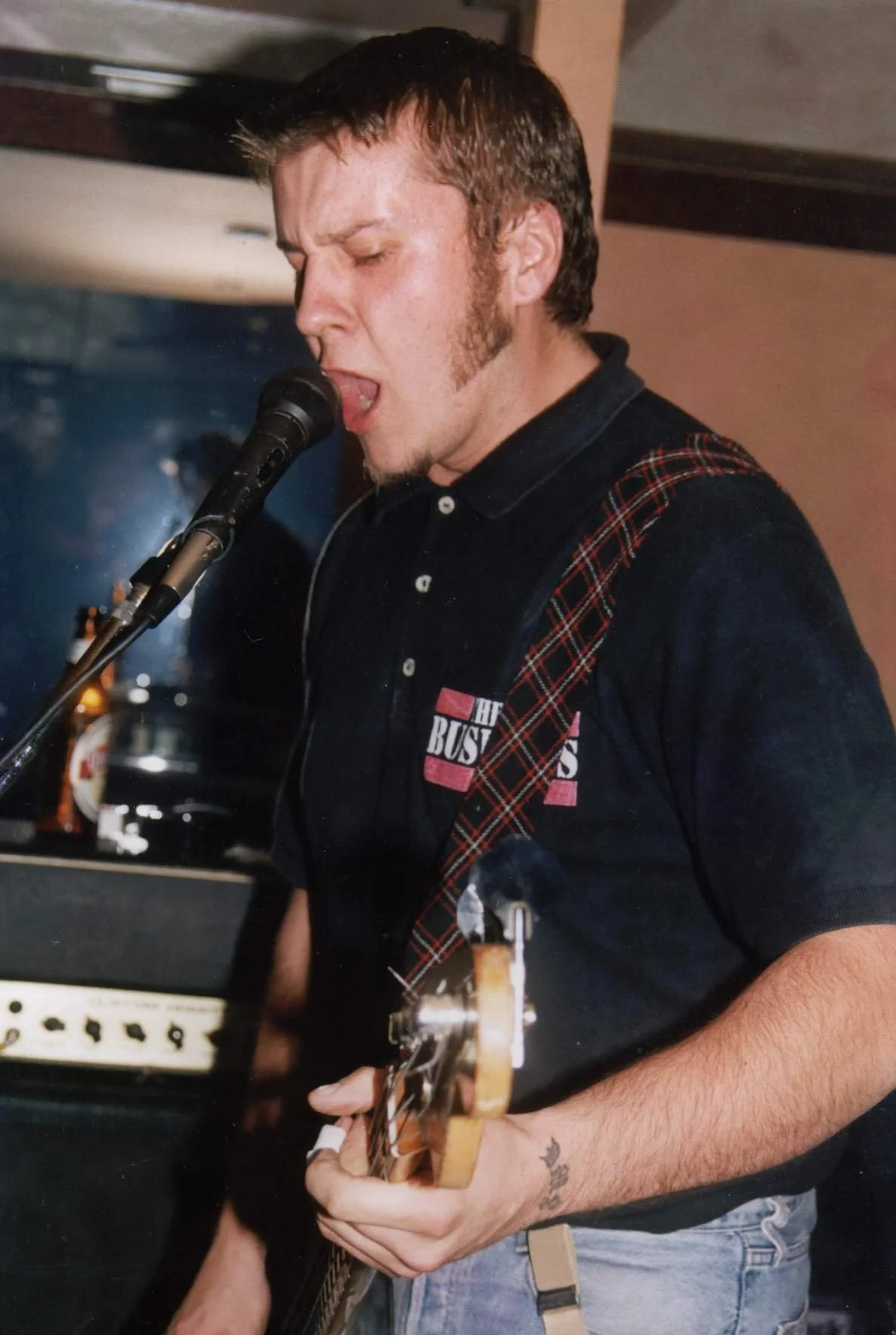 A man singing into a microphone while playing an electric guitar.