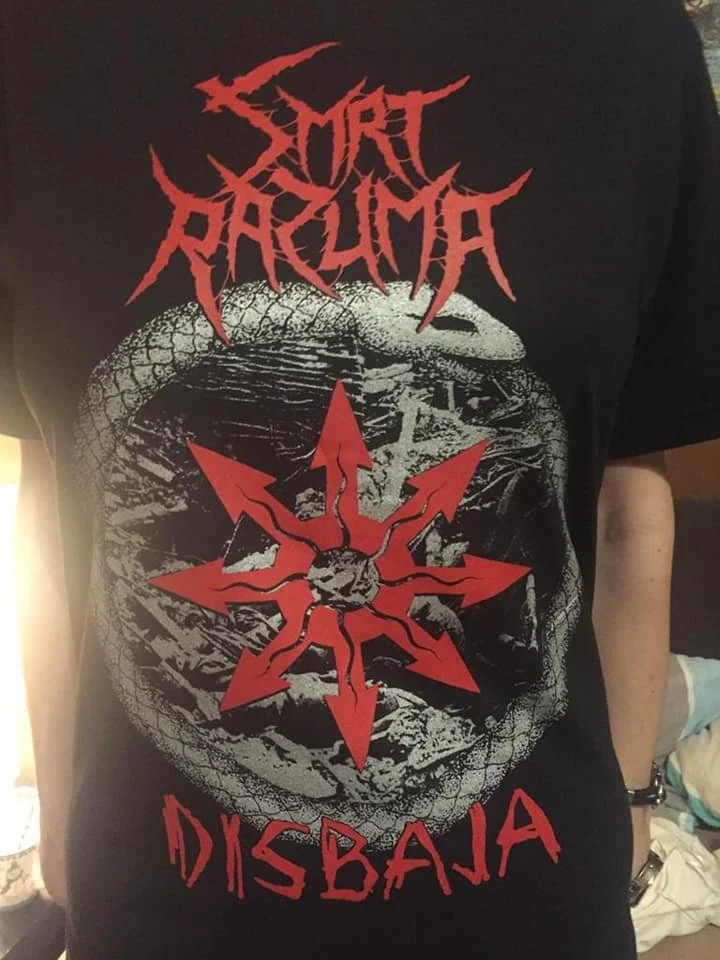 A person wearing a black T-shirt with red and white graphic design. The design features the text ''SMRT RAZUMA" at the top and 'DISBAJA' at the bottom in a jagged font.