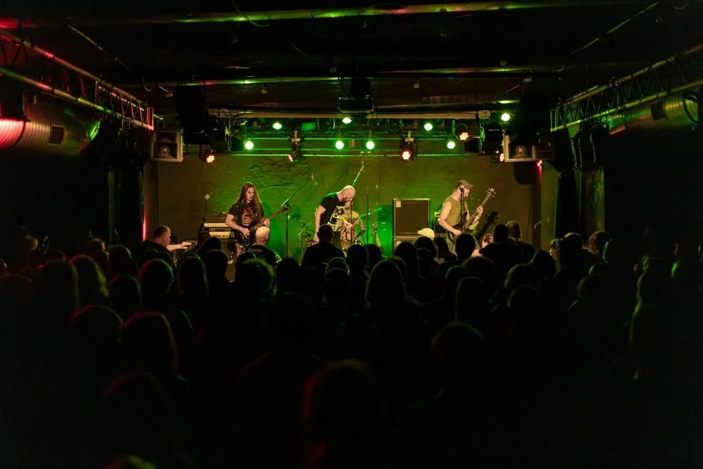 Music band performing on stage at a concert with an audience watching.