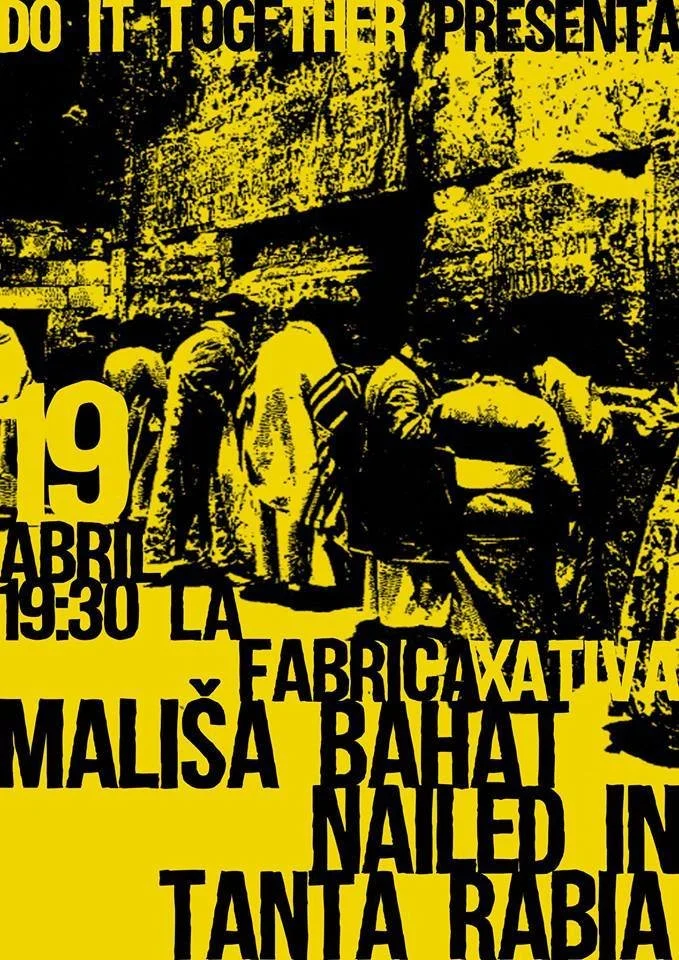People standing in line at a food distribution event in front of an industrial-style building with a large banner.
