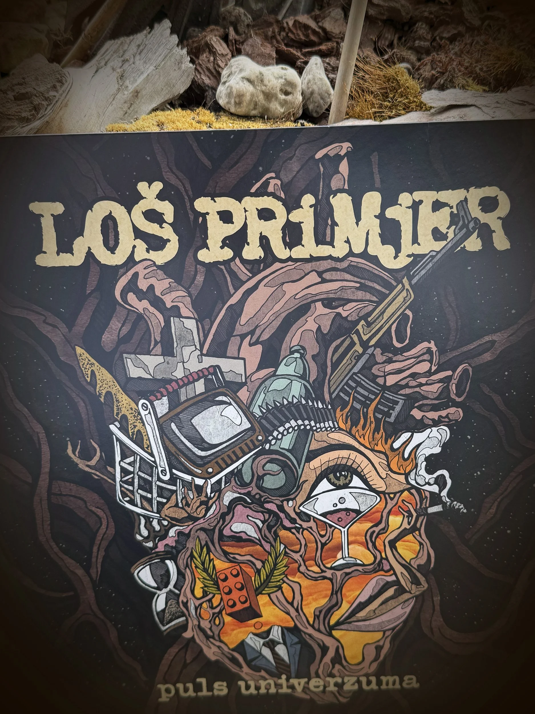 Colorful, artistic illustration featuring the text 'LOS PRIMJER' at the top, surrounded by various objects such as a television, a pair of eyes, a smiling mouth, a goblet, a dice, and other symbolic elements.
