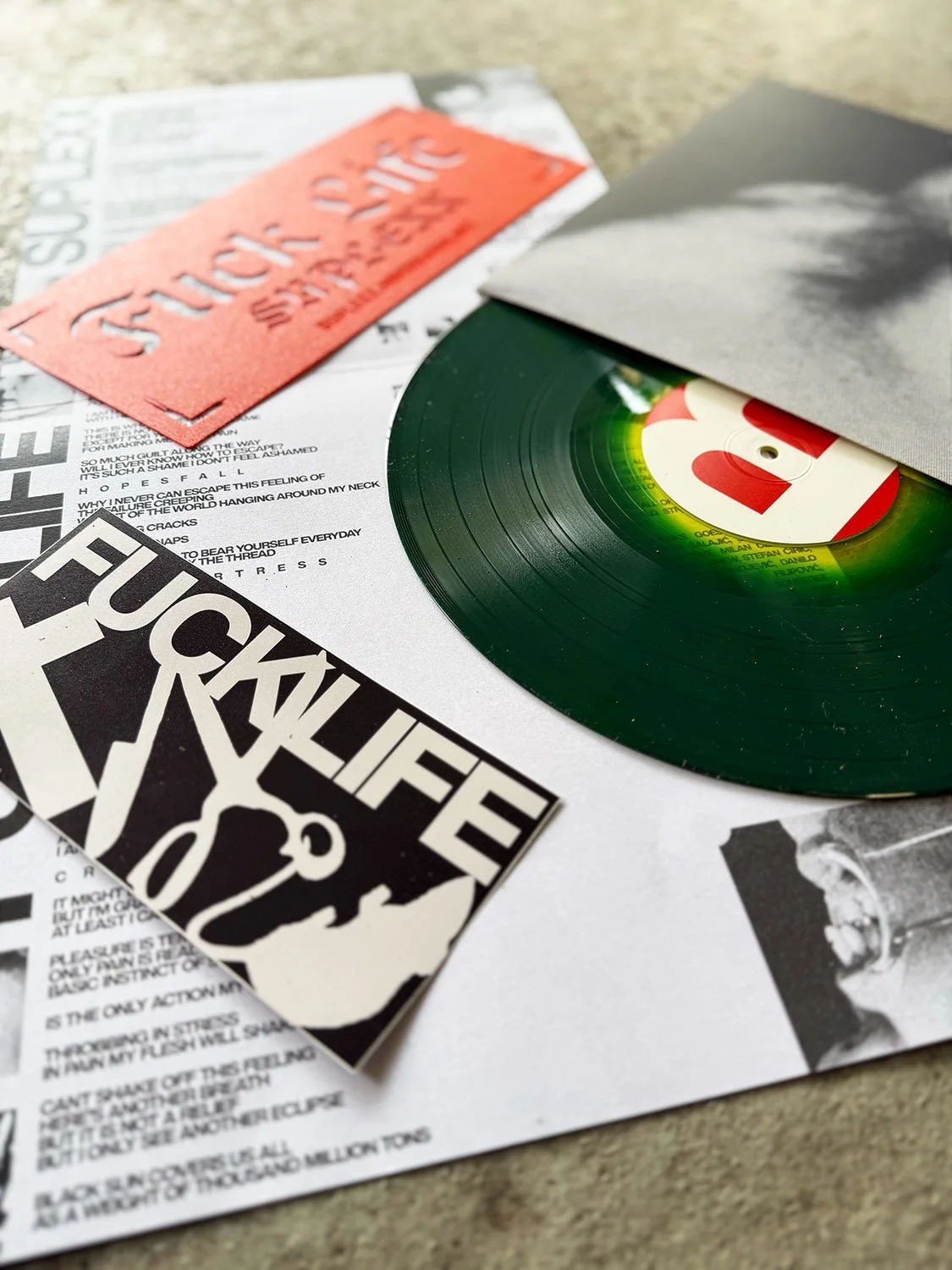 Close-up of a vinyl record and punk rock stickers on a sheet of paper.