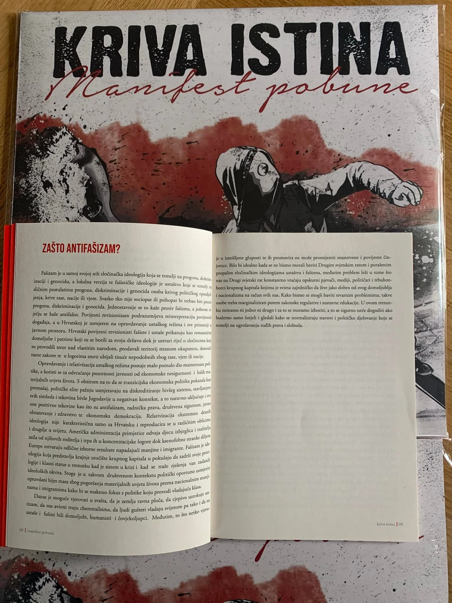 Open book with text and an illustration; ispirational or political illustration with a figure in a hoodie punching or fighting with a large face in the background, with red and black paint splashes.
