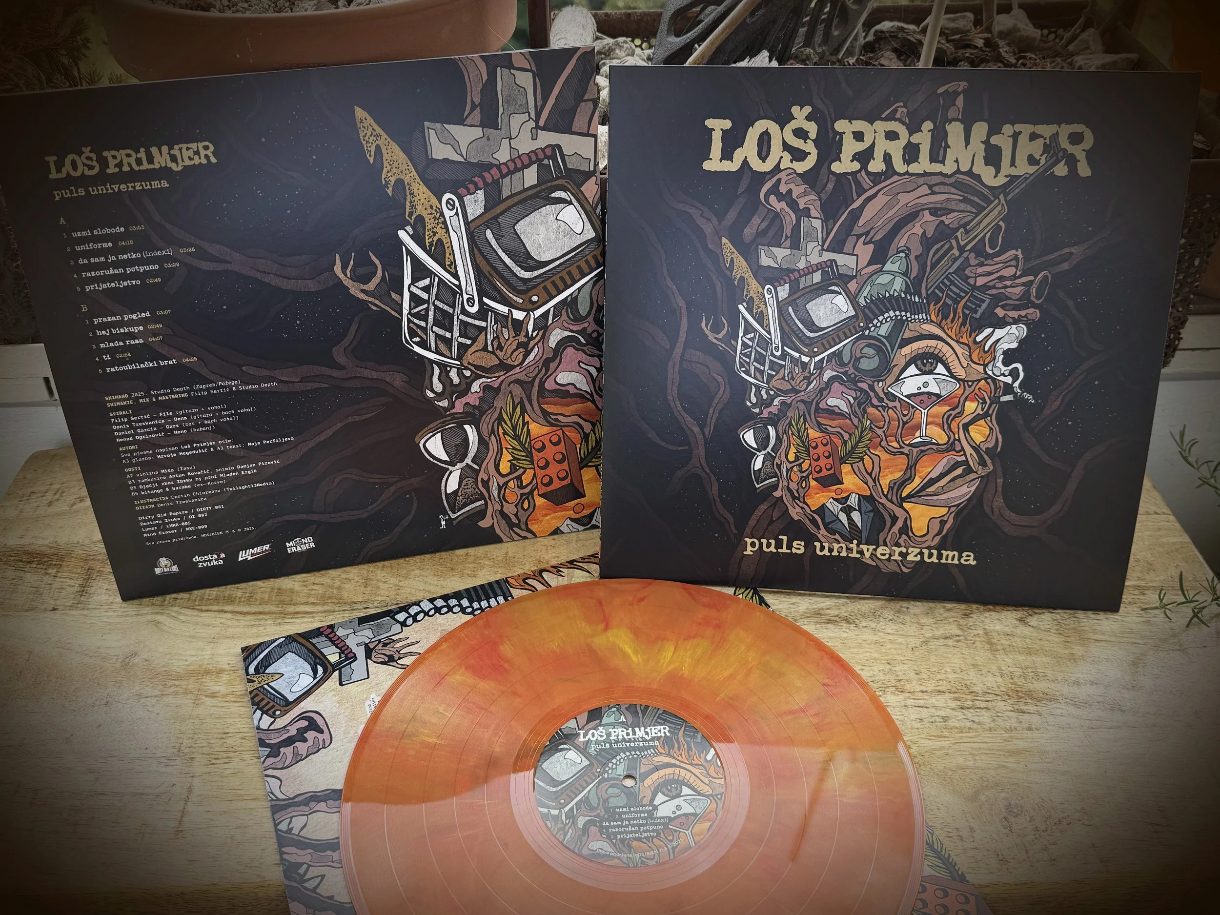 Details of vinyl records and album covers titled 'Los Primjer' with a dark artistic design and a textured background on a wooden surface.