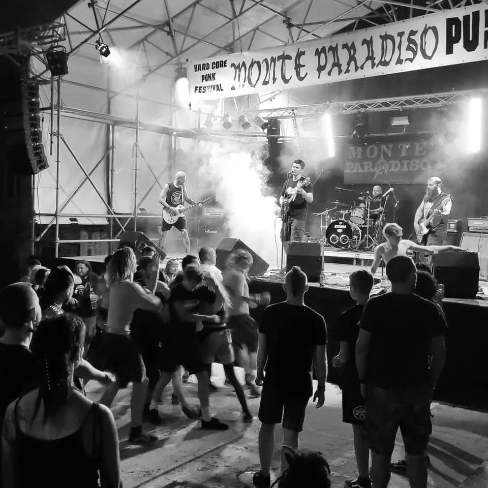 A live concert at Monte Paradiso Punk Festival with a band performing on stage and people dancing in front of the stage.