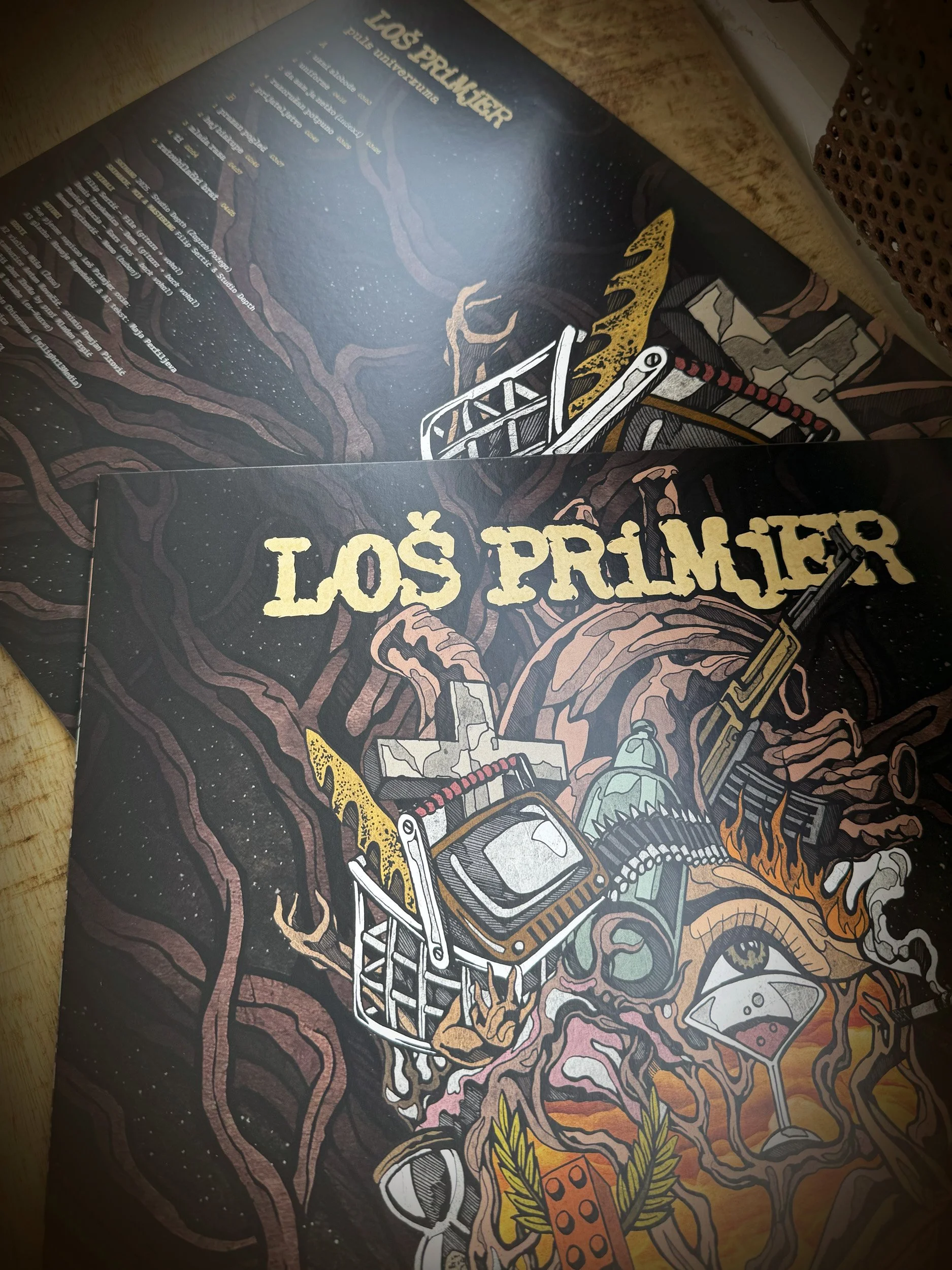 Close-up of a colorful illustrated book cover titled 'Los Primeros' featuring surreal and abstract artwork, including a television, a shopping cart, a snake, an eye, and various other objects entwined in a vibrant and intricate design.