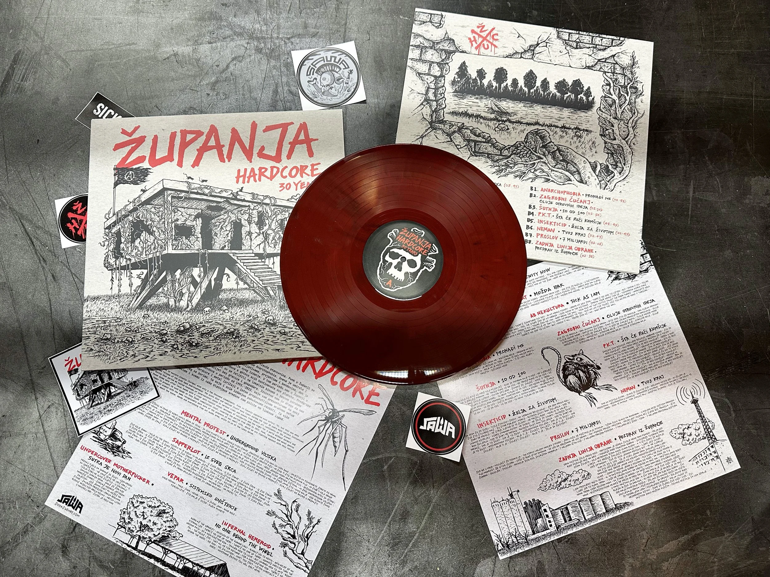 Music records and illustrated flyers, with drawings of a tree, a river, and a house, and text in Croatian, related to a hardcore music event or album.