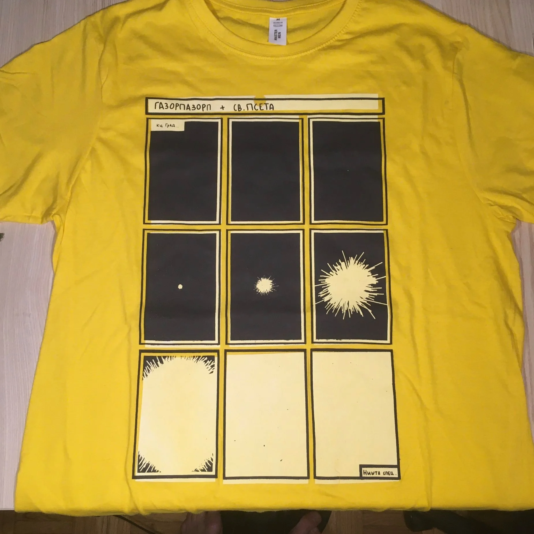 Yellow T-shirt with black comic-style panels and Russian text, featuring explosion graphics, laid flat on a surface.