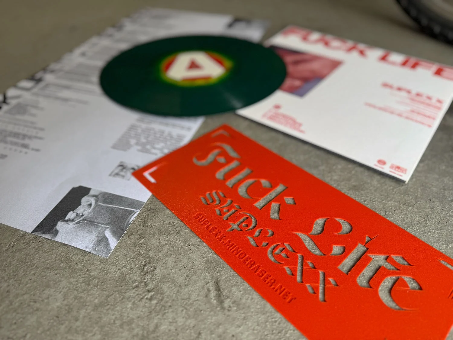 Various printed materials and a green vinyl record on a gray surface.