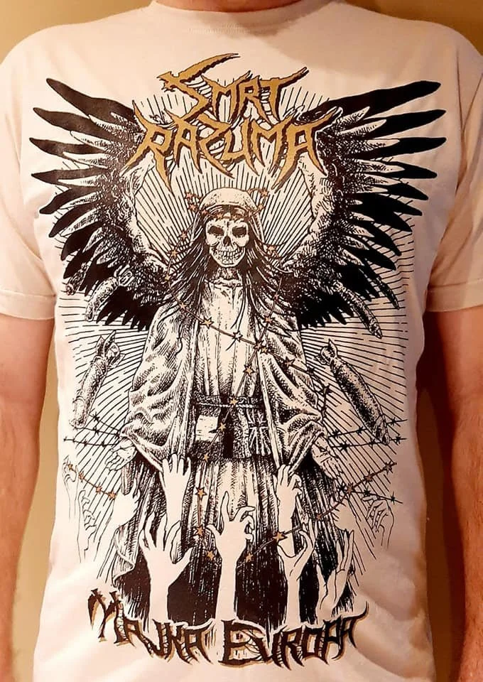 A person wearing a graphic t-shirt featuring a skeletal figure with angel wings, a skull face, and long hair, surrounded by reaching hands, with text that reads "Smrt Razuma" at the top.