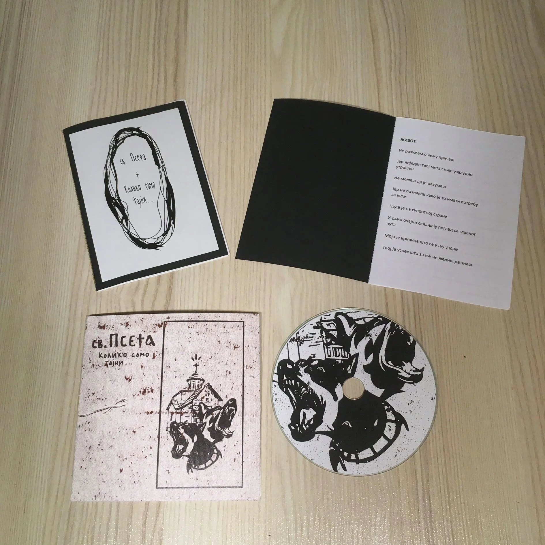 Black and white printed cards and a CD with a similar design on a wooden surface.