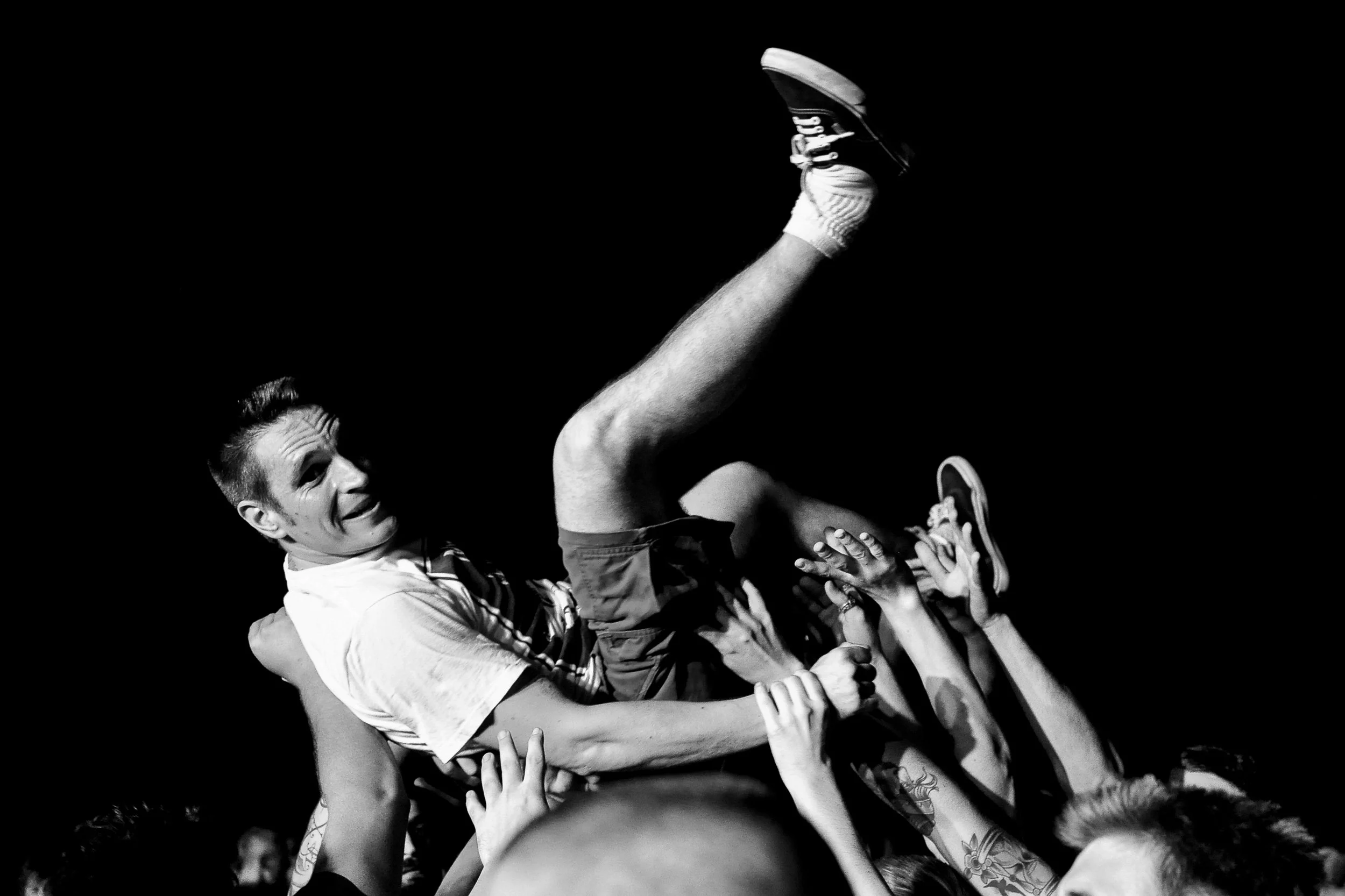 A black-and-white photo of a group of people, with a person being lifted and supported by the crowd, indicating a sense of celebration or achievement.