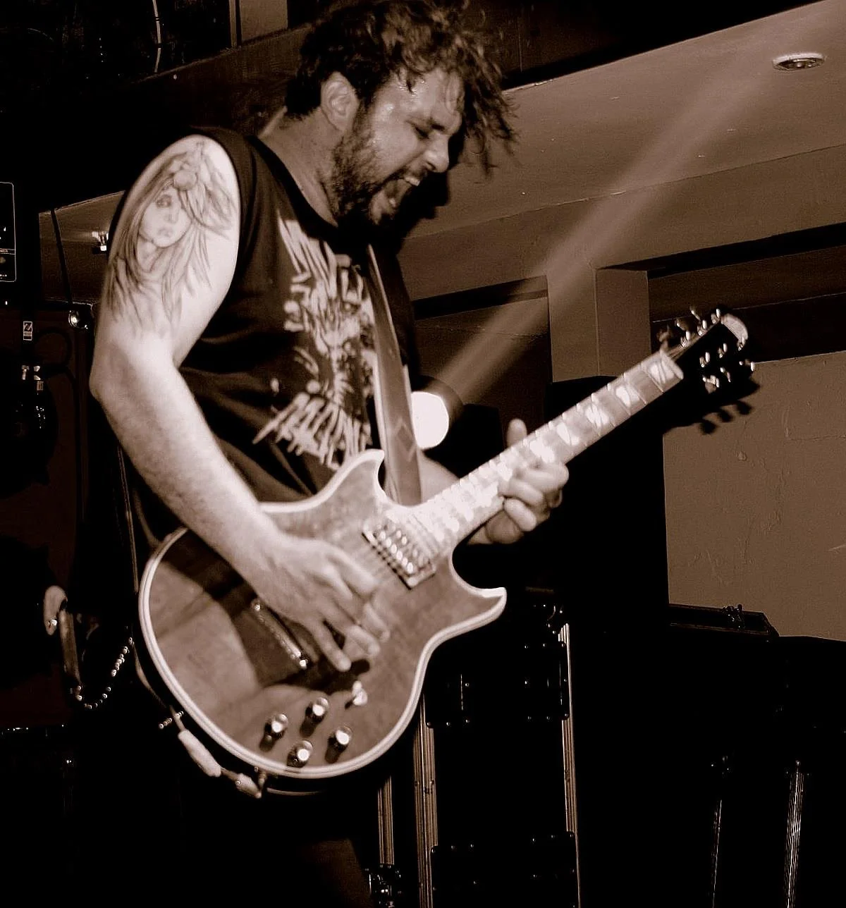 A man with dreadlocks and a beard playing an electric guitar, singing passionately on stage. Band name: 1000mods