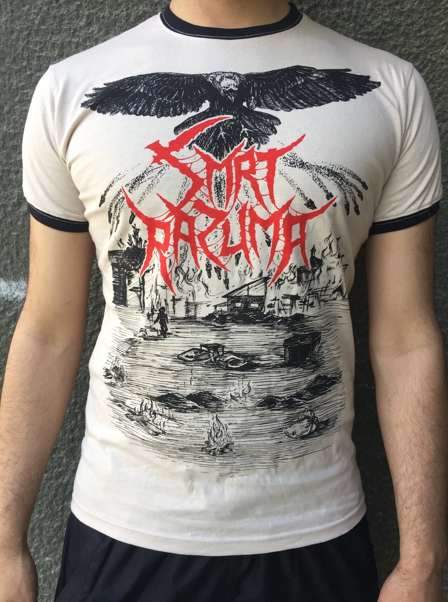 A person wearing a white t-shirt with black and red graphic art featuring an eagle and a cityscape. The graphic includes a black eagle with spread wings above the city, and red and black design elements.