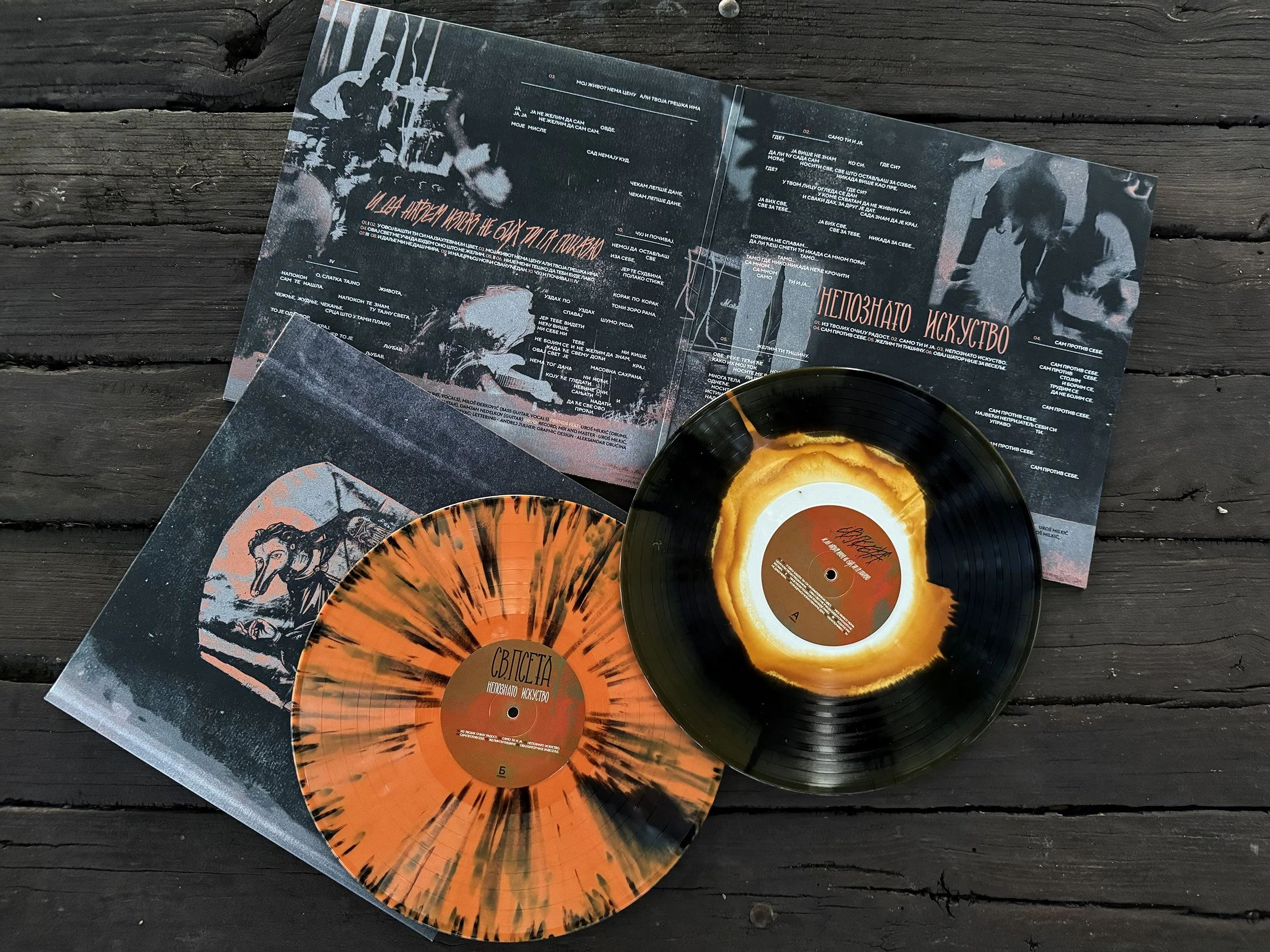 Close-up of vinyl records and album covers on a dark wooden surface, featuring abstract and artistic designs.