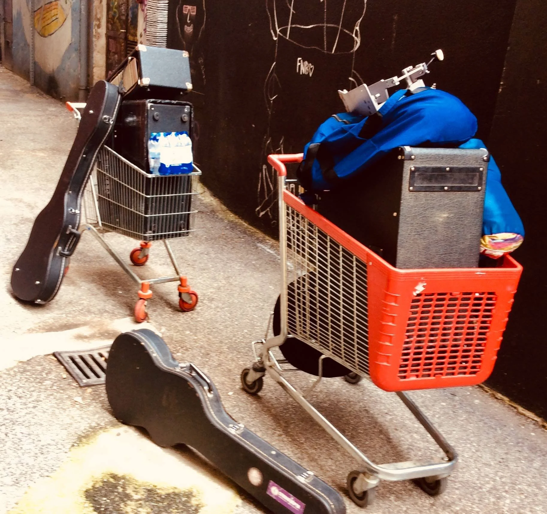 Disorganized shopping carts and skateboards on the ground outside against a dark wall.