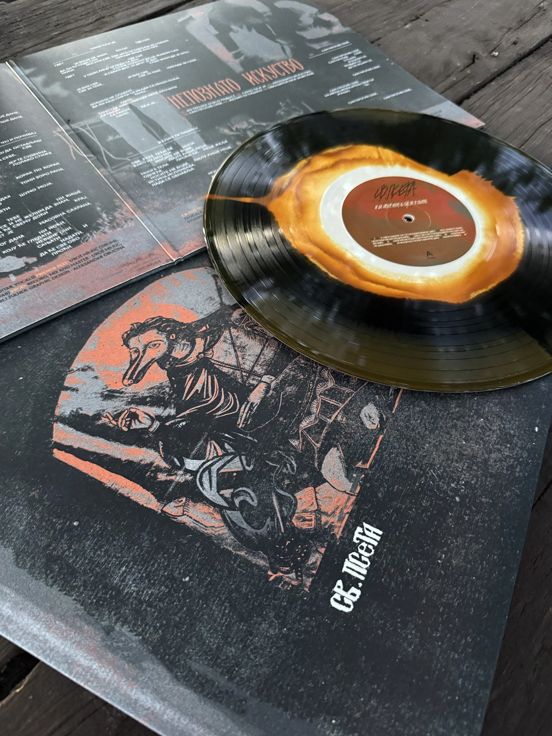 A vinyl record on top of its album cover and sleeve for SV. PSETA, both featuring dark and red artwork with an illustration of a person with a bird-like beak.
