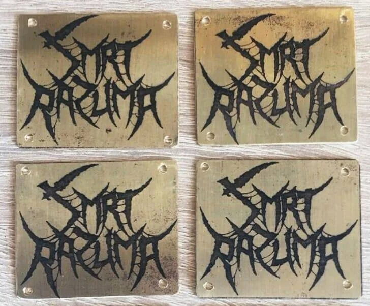 Four square metal plaques with black gothic-style text that reads "SMRT RAZUMA" on a metal surface.