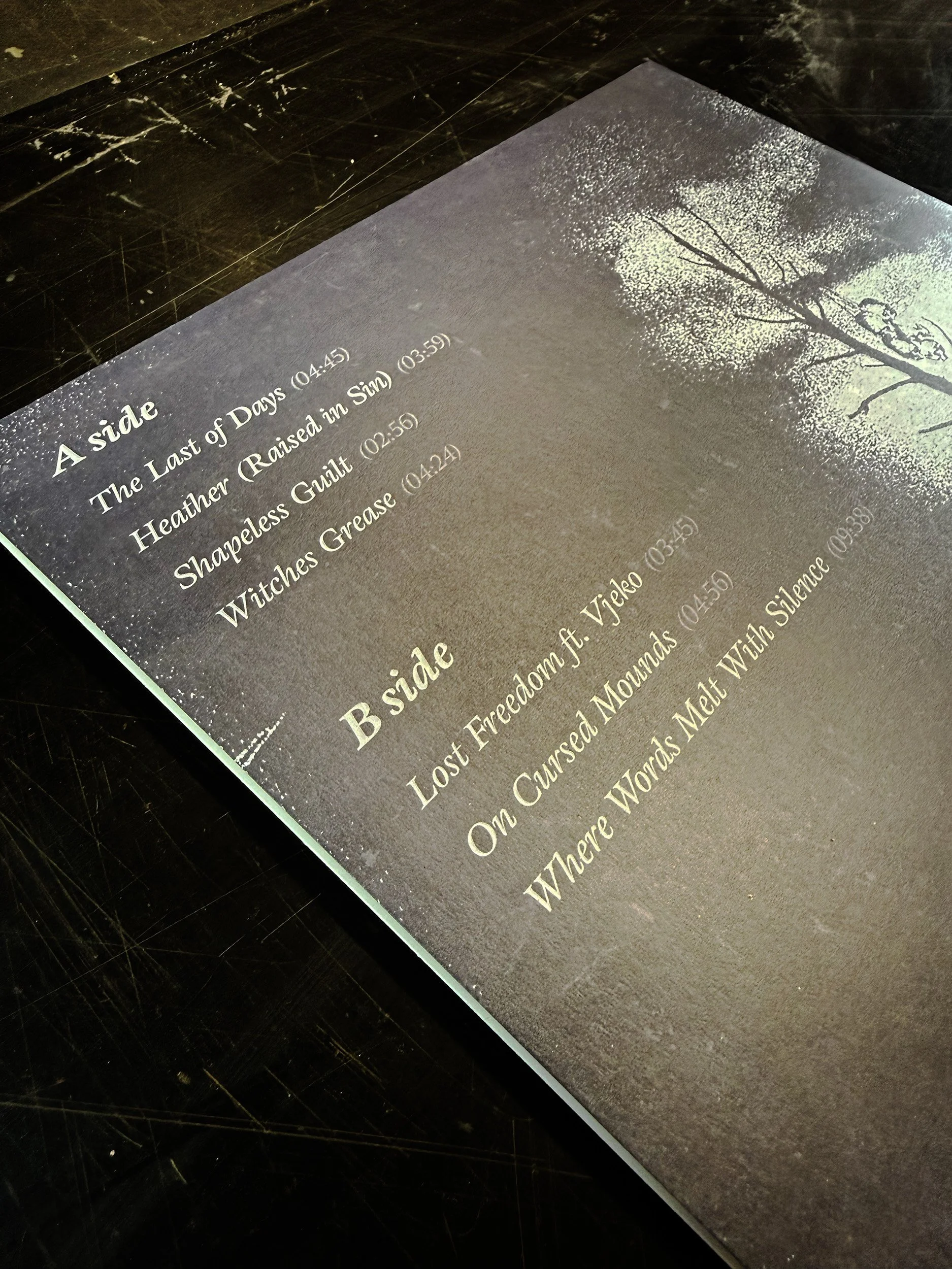 A black memorial plaque with white engraved text and an engraved image of a tree with branches and leaves.